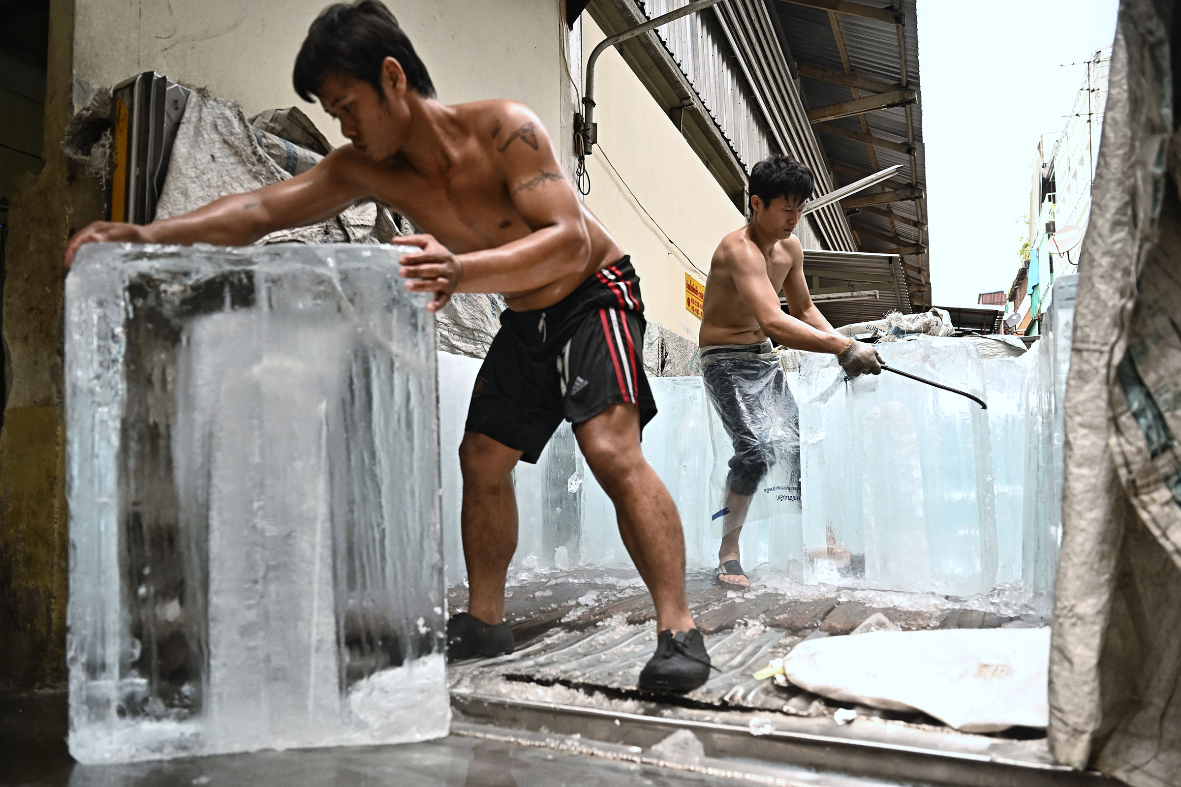 Workers move blocks of ice into a storage unit at a fresh market amid a heatwave in Bangkok, Thailand, on April 25. (Lillian Suwanrumpha—AFP/Getty Images)