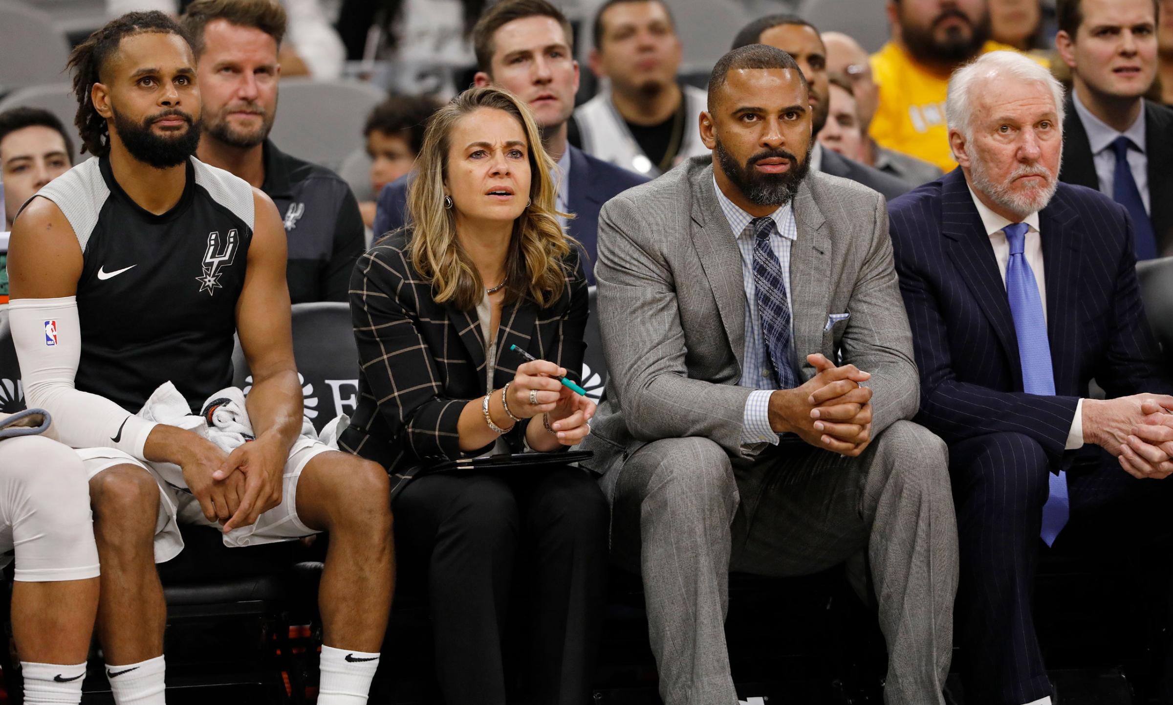 Hammon and Spurs guard Patty Mills on the bench next to head coach Gregg Popovich, right, and assistant coach Ime Udoka