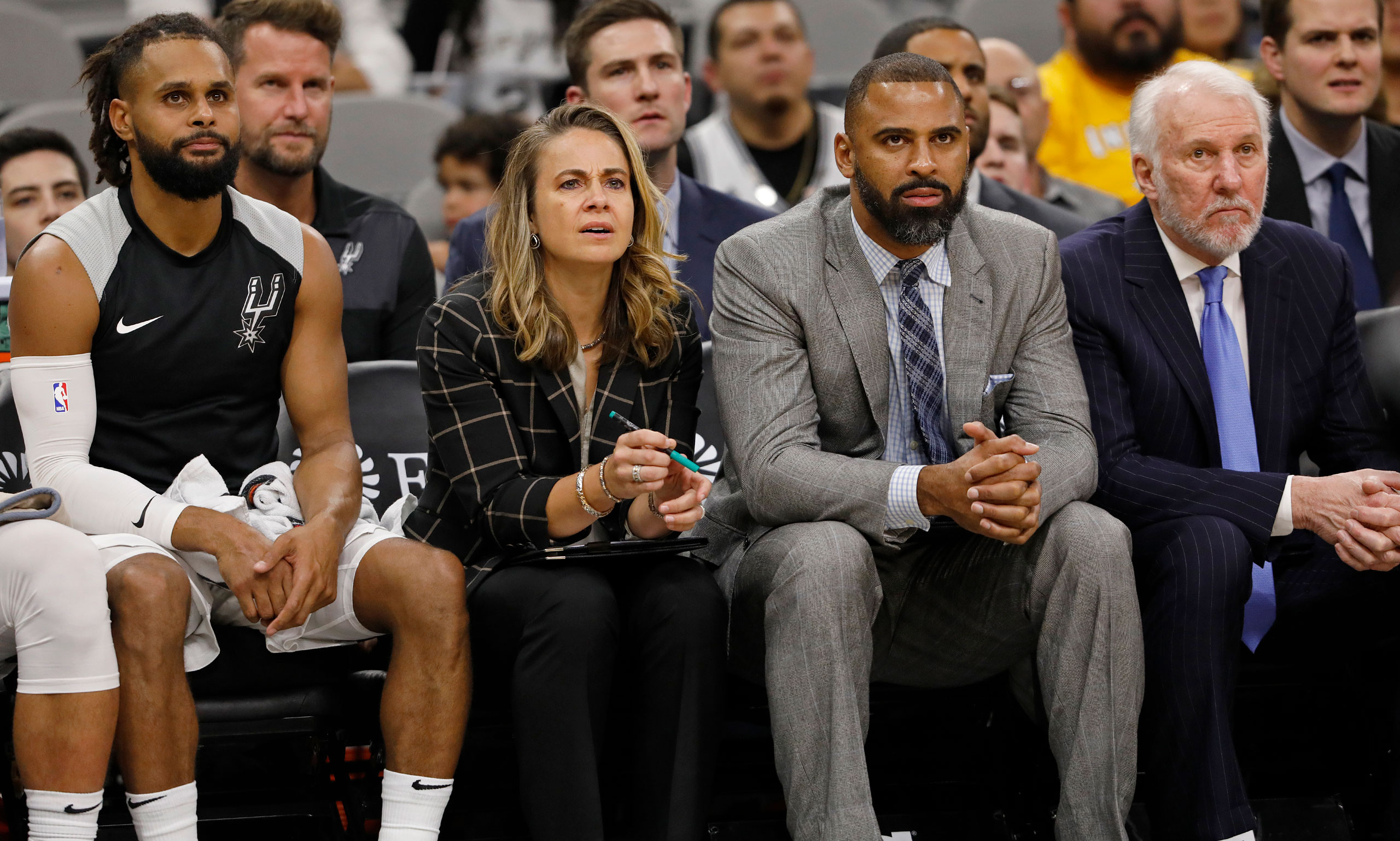 Hammon and Spurs guard Patty Mills on the bench next to head coach Gregg Popovich, right, and assistant coach Ime Udoka, now the head coach of the Houston Rockets. (Edward A. Ornelas—Getty Images)