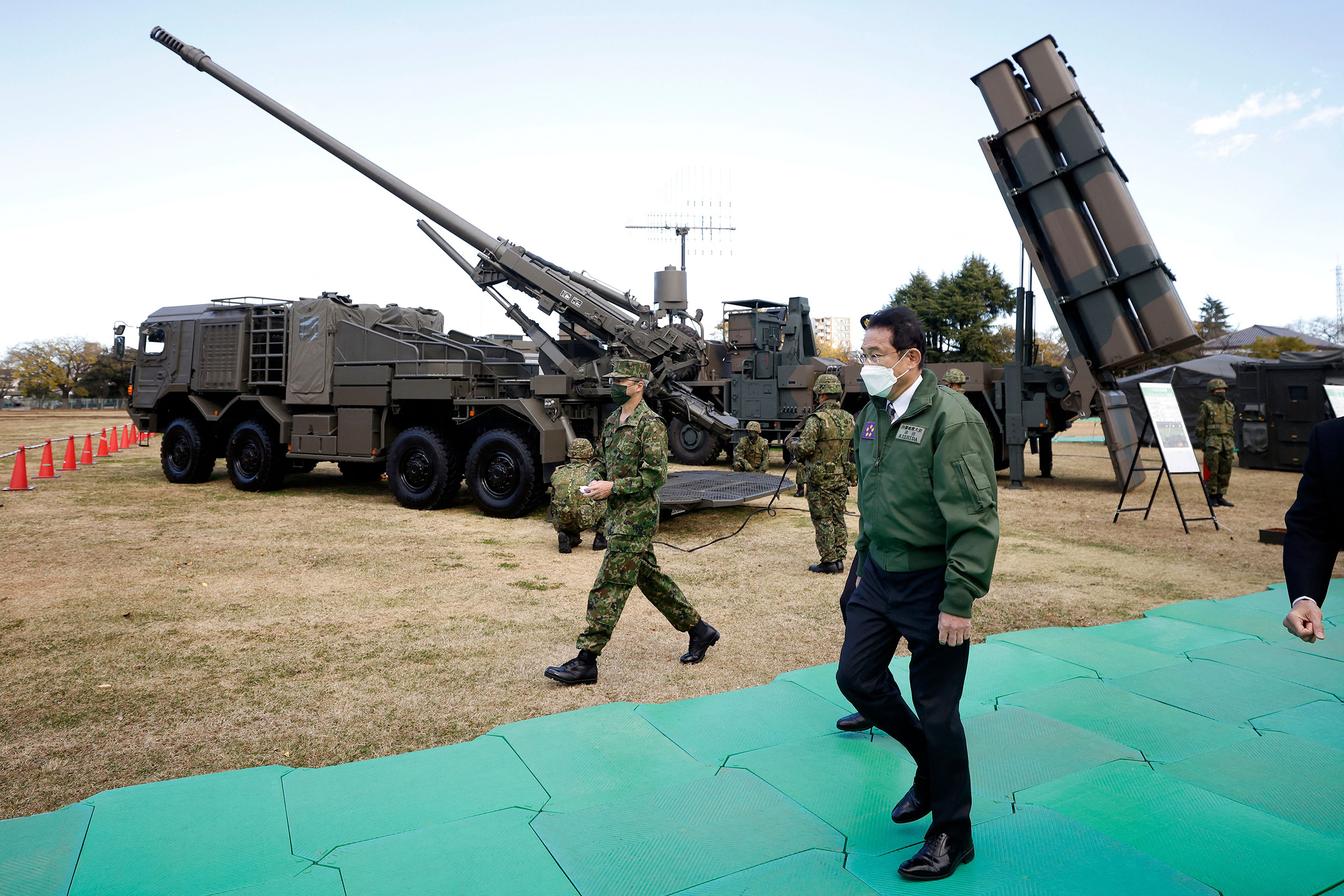 Prime Minister Kishida walks past a Japan Ground Self-Defense Force (JGSDF) Type 19 155 mm wheeled self-propelled howitzer and a Type 12 surface-to-ship missile as he inspects equipment during a review at JGSDF Camp Asaka in Tokyo on Nov. 27, 2021. (Kiyoshi Ota—Pool/AFP/Getty Images)