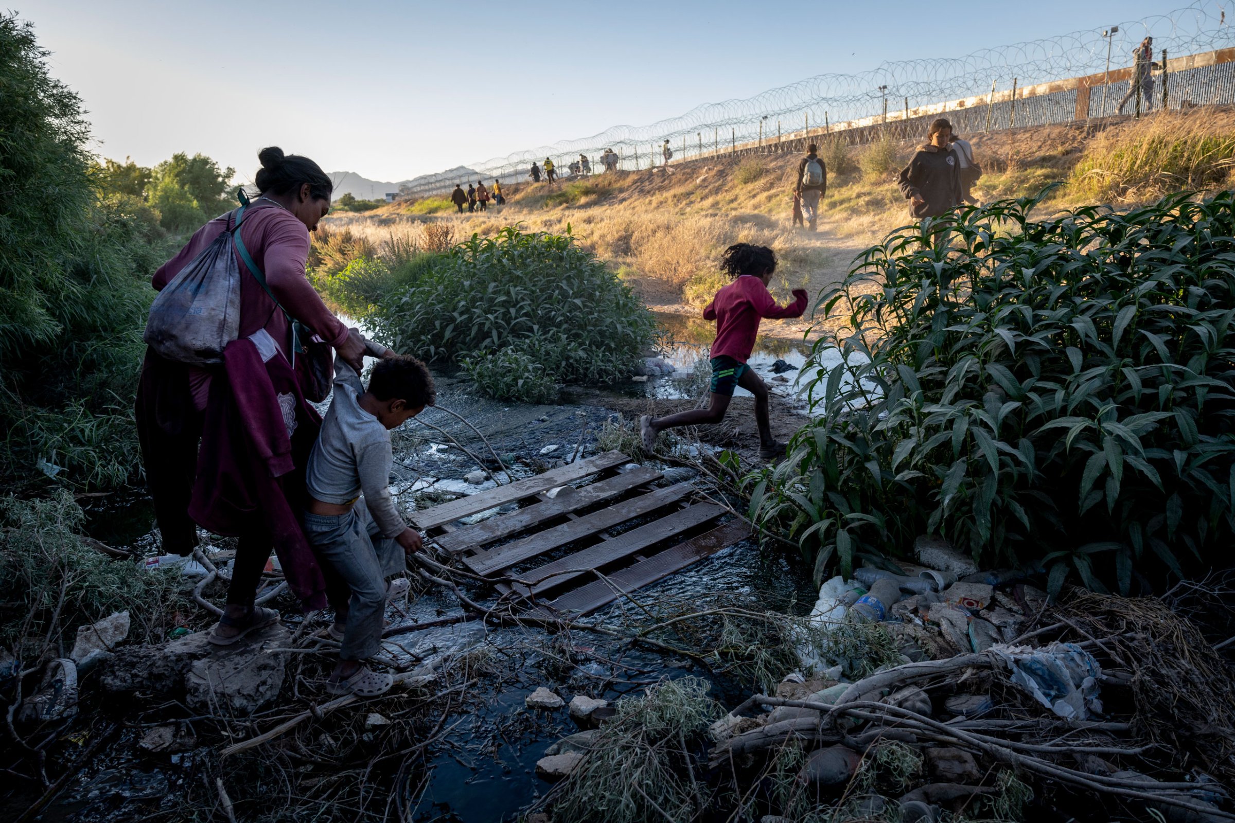 Immigrants step over a trickle of the Rio Grande while crossing the border from Mexico hoping to be processed for asylum in El Paso, Texas, on May 08, 2023.