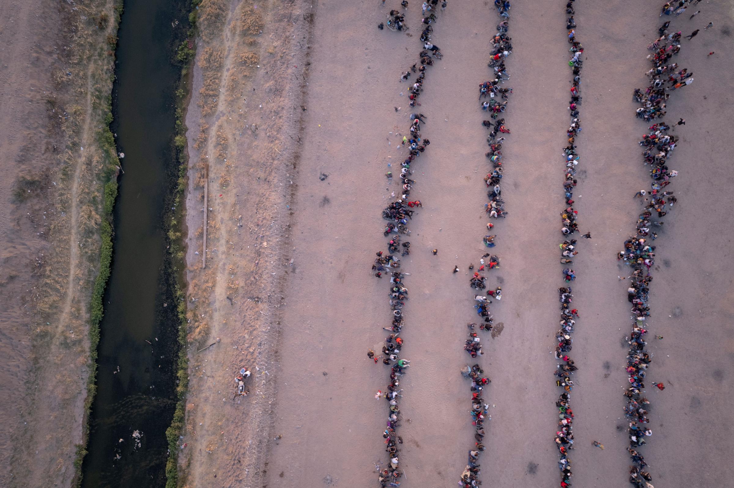 seen from an aerial view, immigrants wait to be processed to make asylum claims after crossing the Rio Grande from Mexico into El Paso, Texas