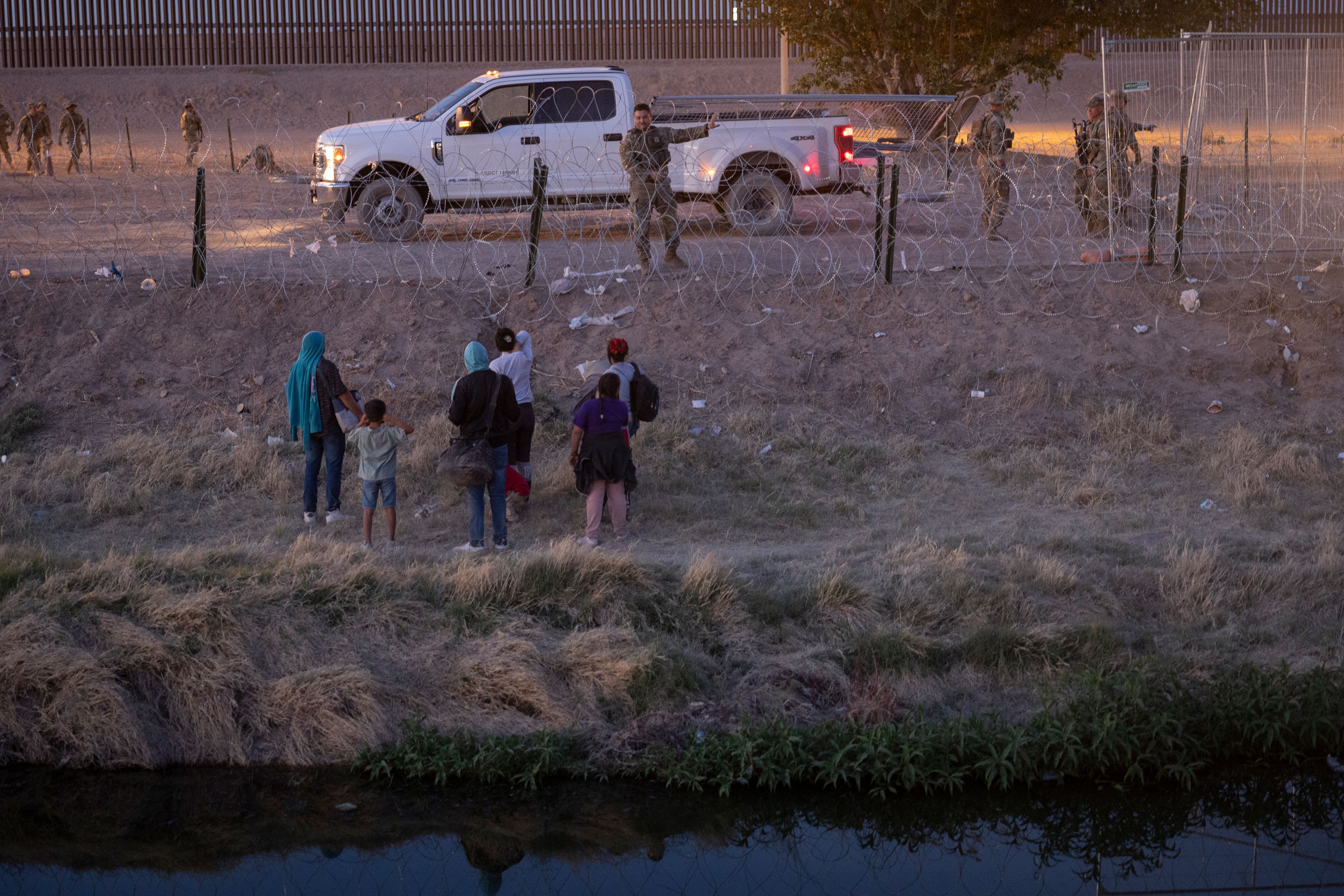 Immigrants speak with Texas National Guard troops after crossing over from Mexico into El Paso, Texas, on May 9, 2023. (John Moore—Getty Images)