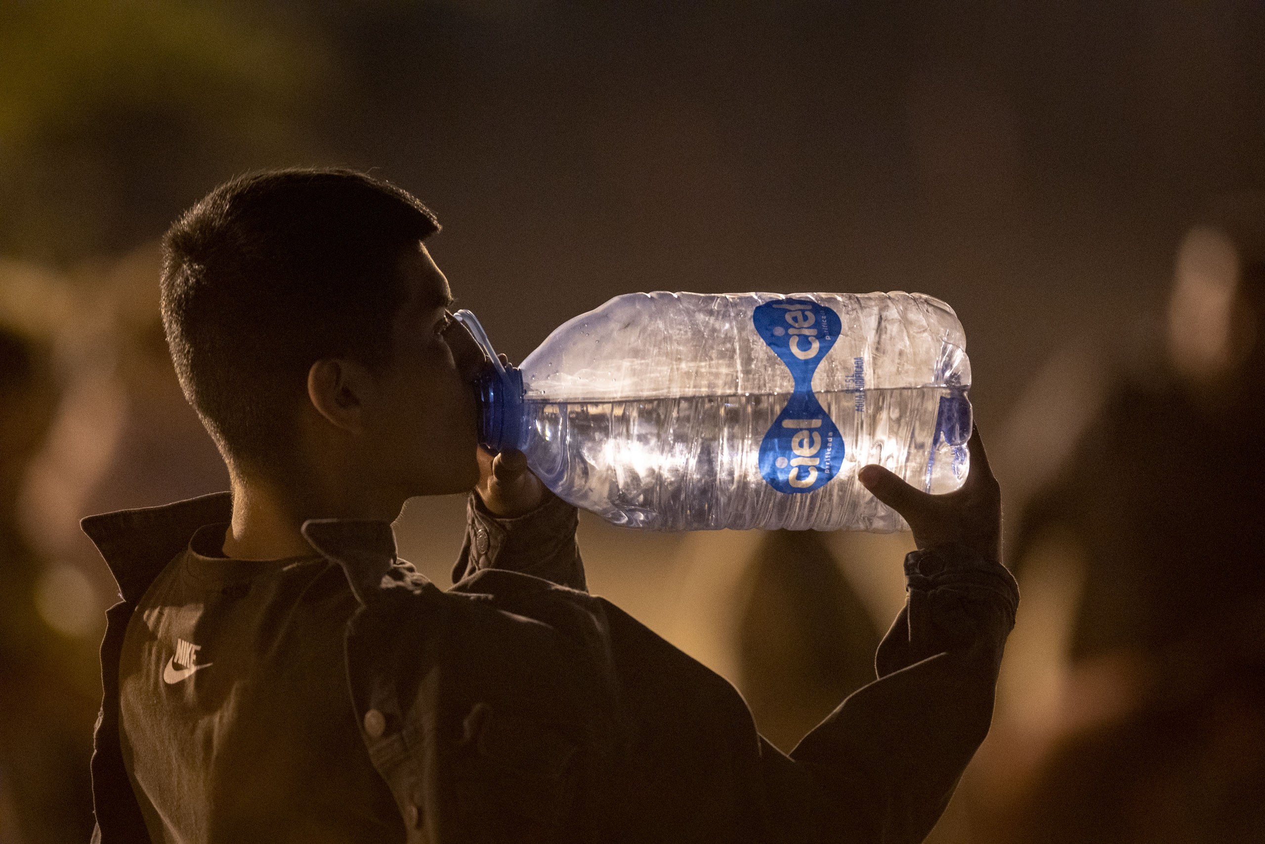An immigrant hydrates after crossing into the United States from Mexico on May 9, 2023. (John Moore—Getty Images)