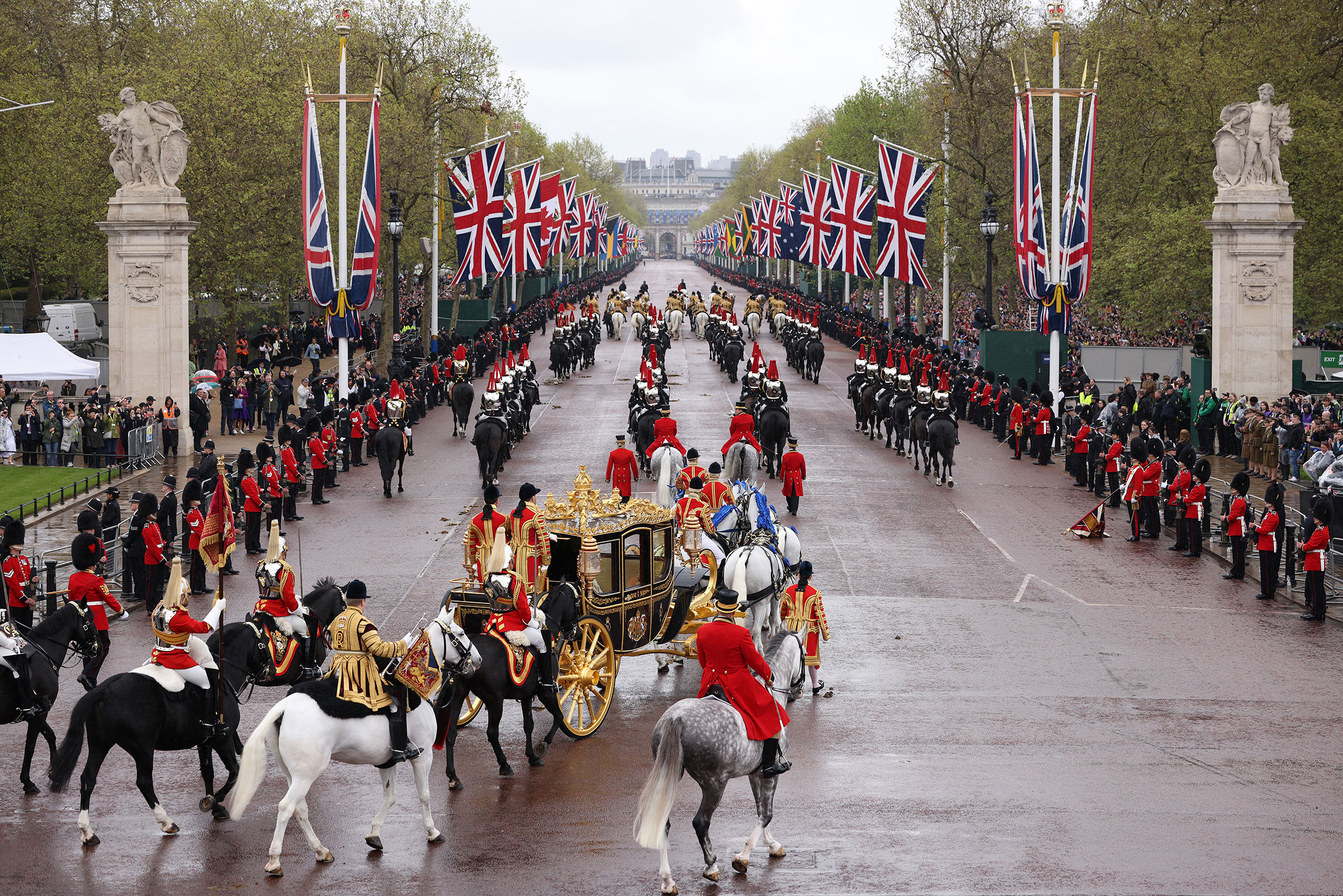 King Charles III and Camilla, Queen Consort, traveling in the Diamond Jubilee Coach, flanked by over a thousand Armed Forces route liners and The Sovereign’s Escort of the Household Cavalry sets off along the Mall from Buckingham Palace on route to Westminster Abbey. (Dan Kitwood—Getty Images)
