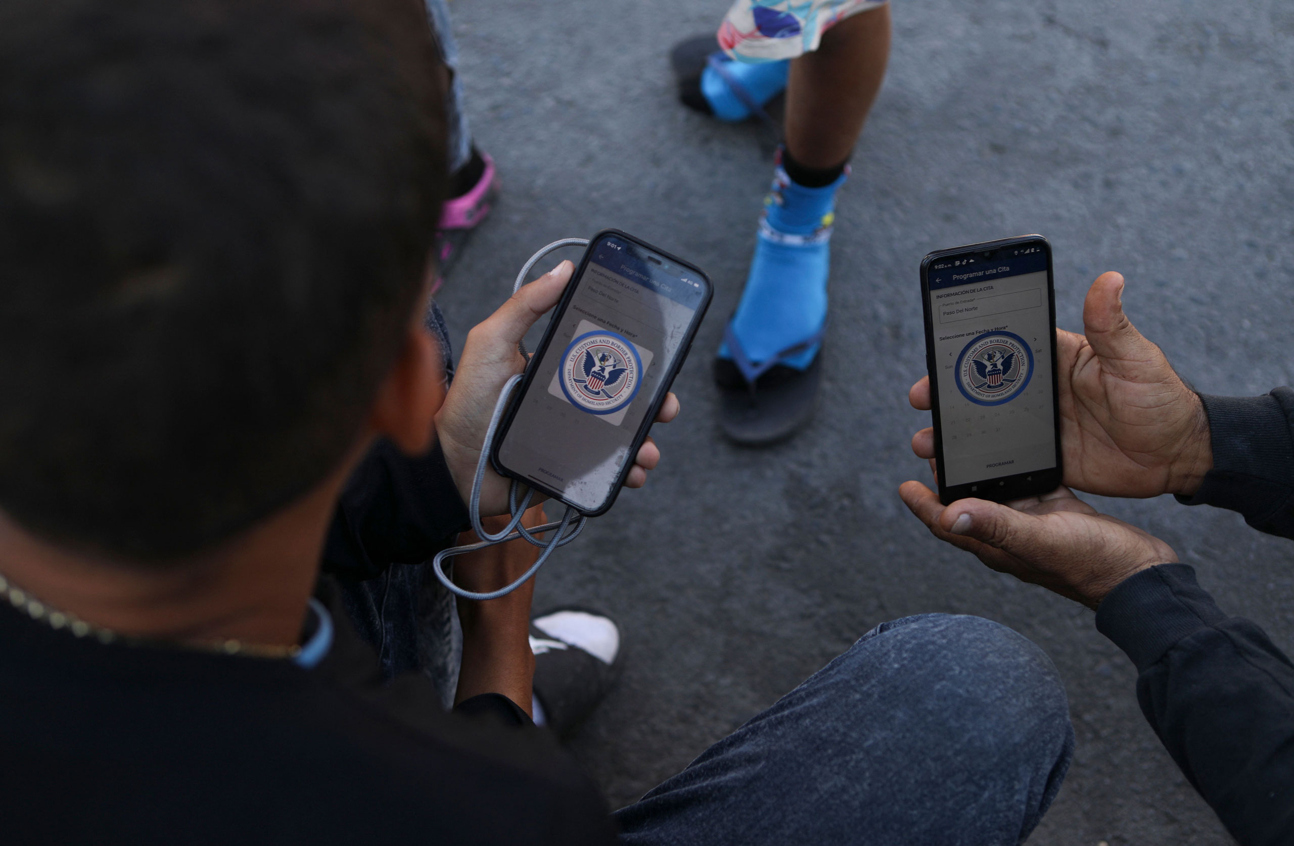 Venezuelan migrants browse the CBP One mobile app searching for an appointment to enter the United States outside the temporary stay of the National Migration Institute (INM) in Ciudad Juarez, Mexico, on May 5, 2023. (Herika Martinez—AFP/Getty Images)