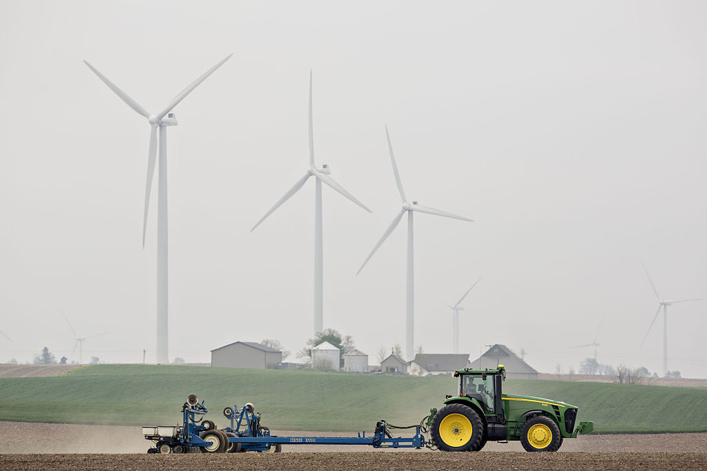 A tractor works in a corn field in Tiskilwa, Illinois, on April 26, 2016, in front of wind turbines. (Daniel Acker/Bloomberg—Getty Images)