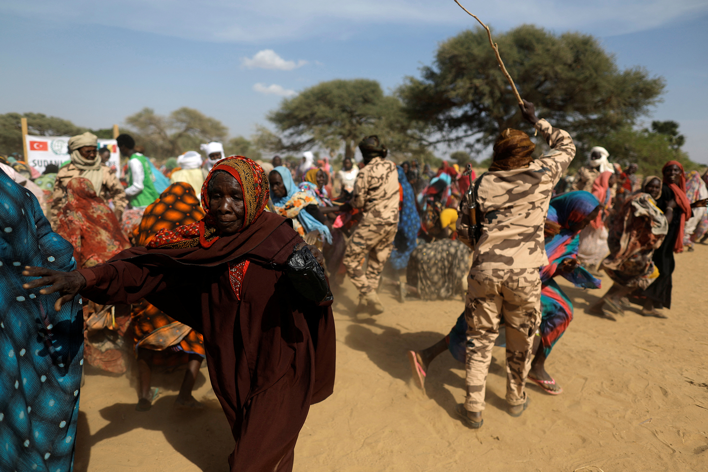 Ülkelerindeki şiddet olaylarından kaçan ve çaresizce gıda dağıtımını bekleyen Sudanlı mülteci kadınlar, Türk yardım örgütünün (İHH) getirdiği erzağın tükenmekte olduğunu görünce kendilerini alıkoymaya çalışan askerlerin erzak çantalarını kapmaktan sıyrılıyor. , 7 Mayıs'ta Sudan ve Çad arasındaki sınırın yakınında. (Zohra Bensemra—Reuters)