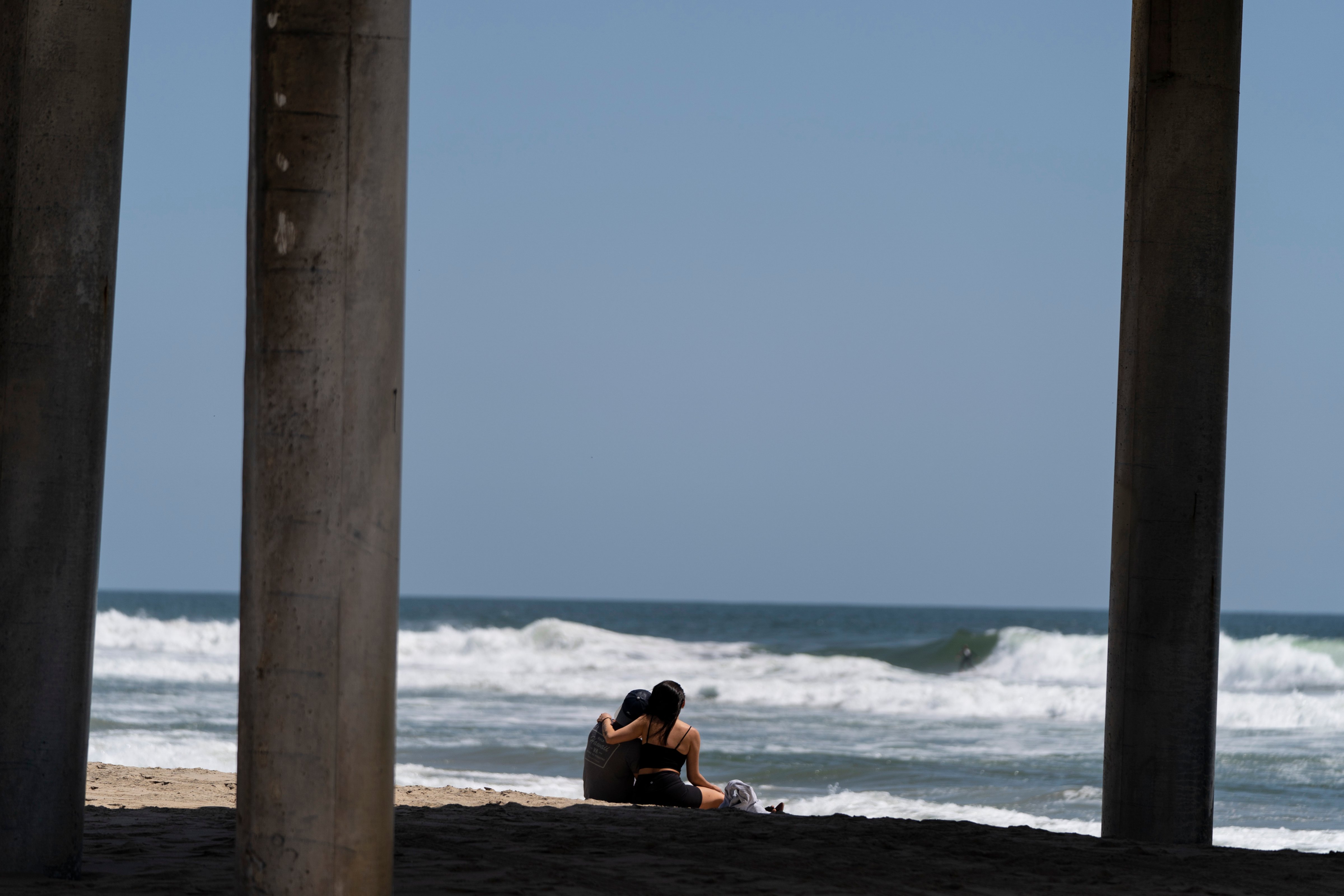 A young couple sit on the beach in Huntington Beach, Calif., on, May 8, 2023. (Jae C. Hong—AP Photo)