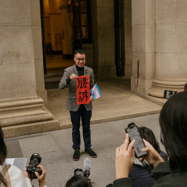 Henry Edward Tse holds a sign saying 'Legal Victory' and a transgender flag while speaking to reporters outside of the Court of Final Appeal in Hong Kong, Feb. 6, 2023.