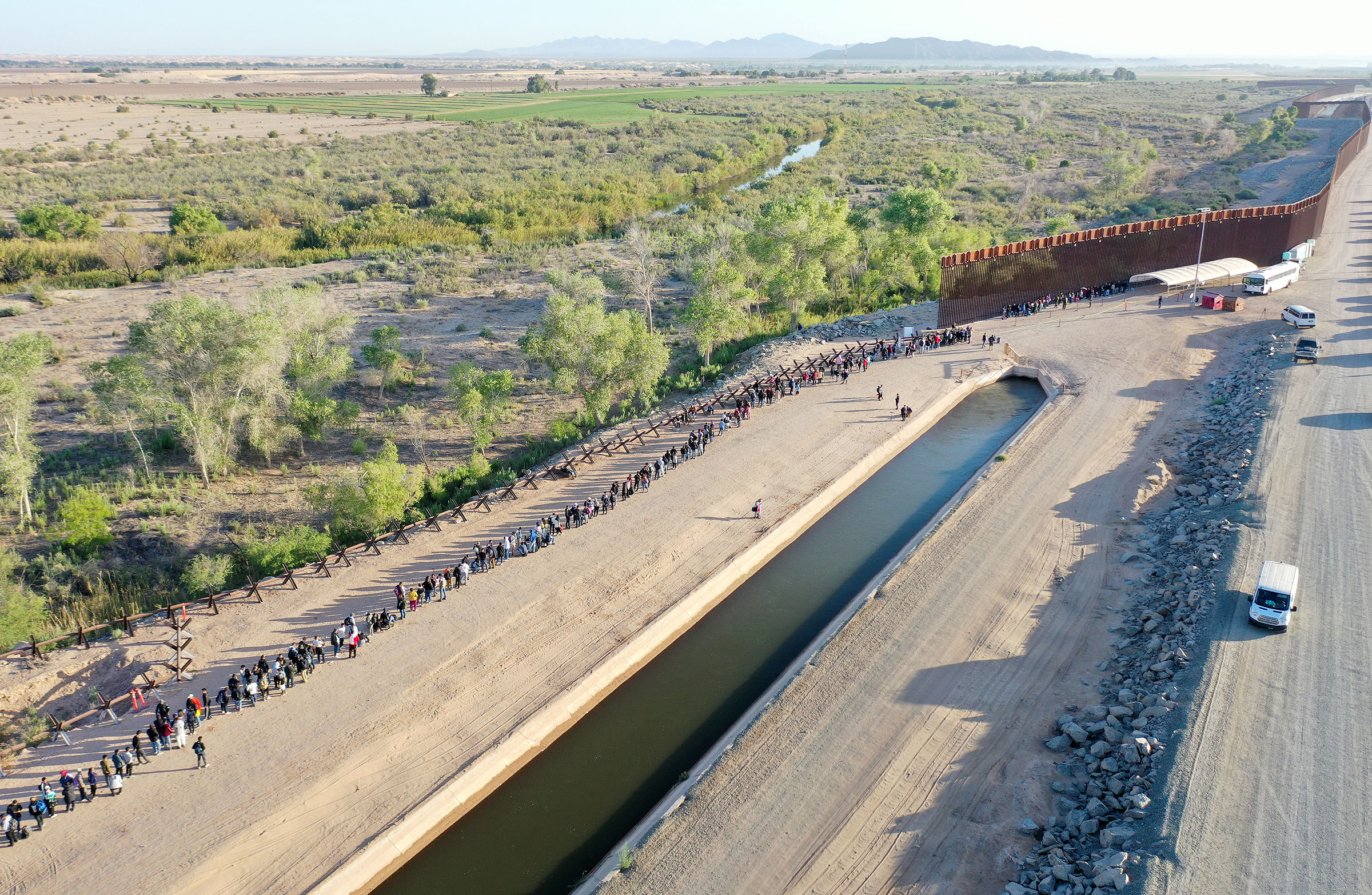 In an aerial view, immigrants seeking asylum in the United States wait in line near the border fence to be processed by U.S. Border Patrol agents after crossing into Arizona from Mexico in Yuma, Arizona, on May 11, 2023.
