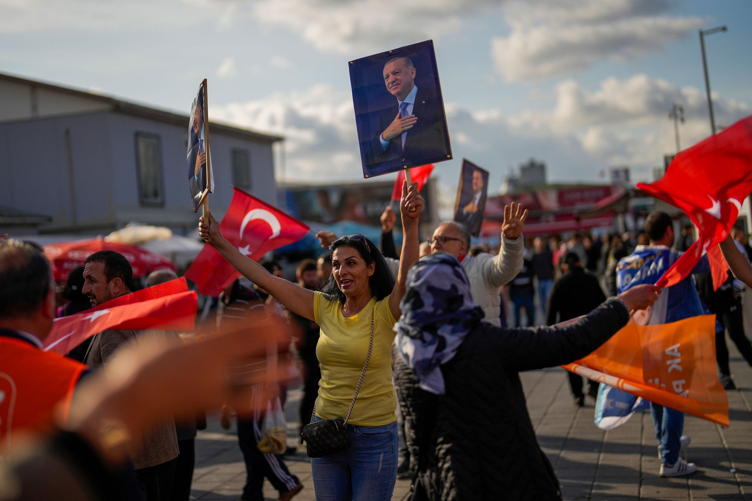 Supporters of Turkish President and People’s Alliance’s presidential candidate Recep Tayyip Erdogan dance as they give handouts to commuters in Istanbul