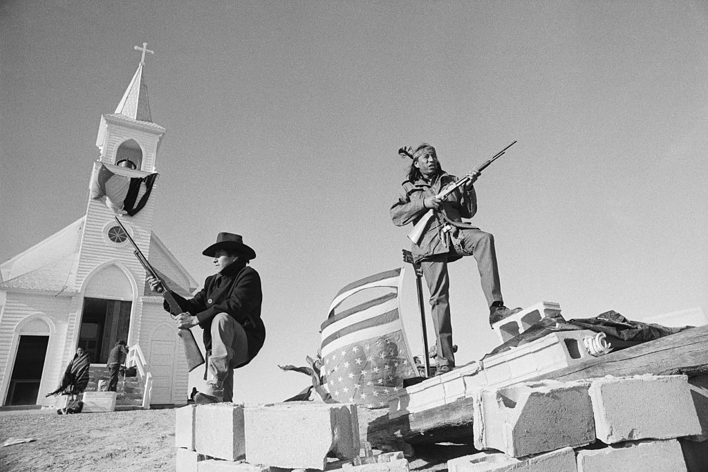 Members of the American Indian Movement and local Oglala Sioux stand guard outside the Sacred Heart Catholic Church after taking control of the town during a 71 day standoff with the FBI and US Marshals. (Bettmann Archive/Getty Images)