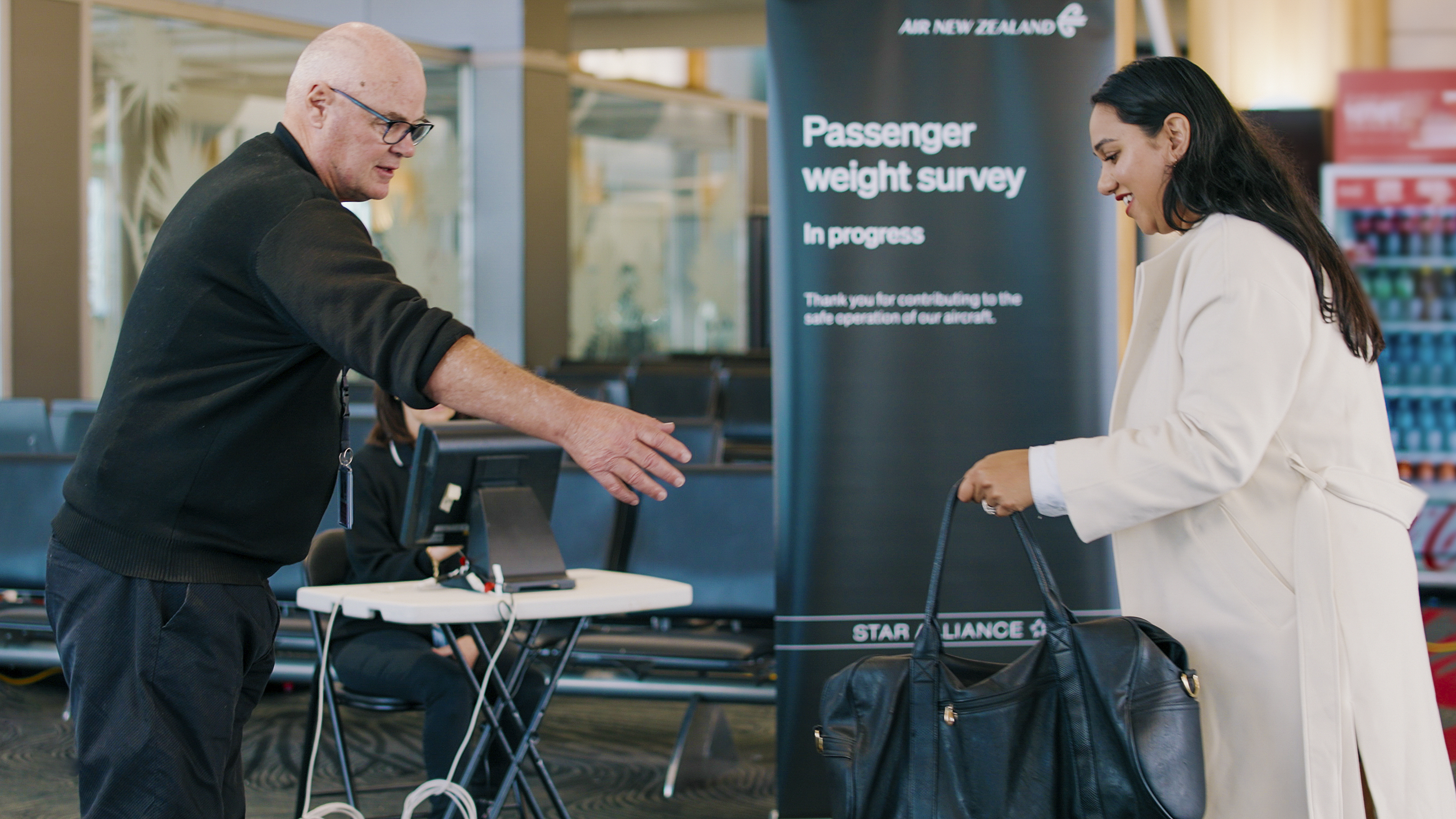 A woman hands her bag to a staff member to be weighed ahead of a flight in Auckland, New Zealand, on May 29, 2023. (Air New Zealand—AP)
