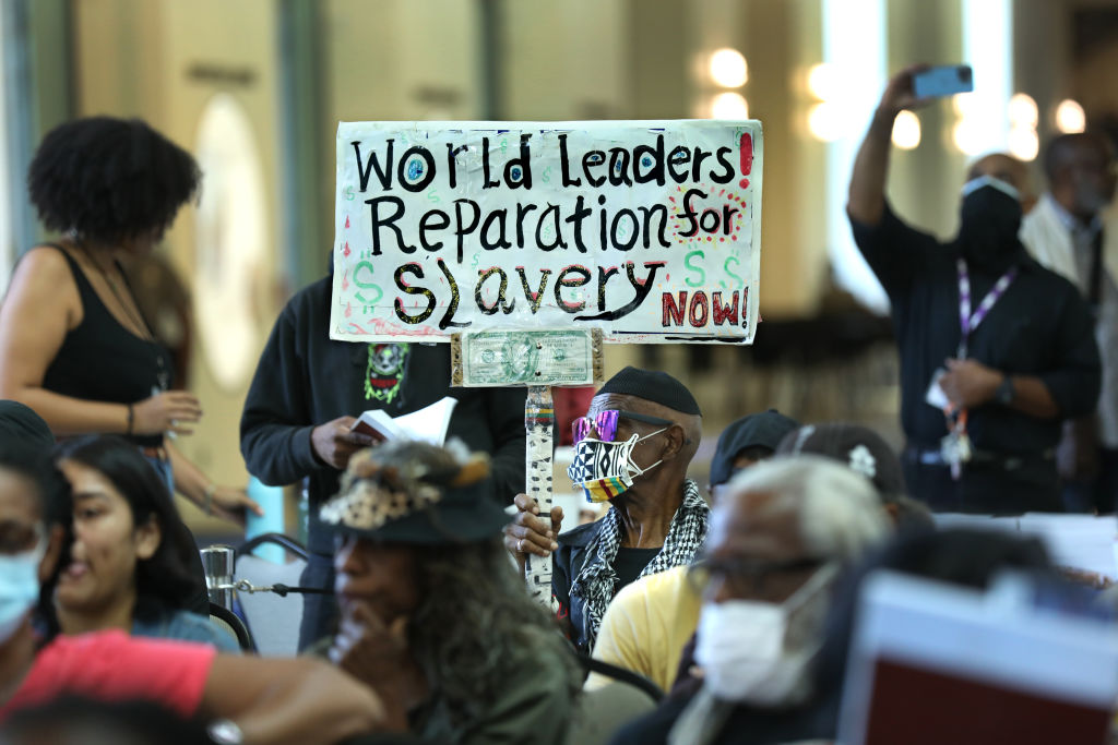 Los Angeles resident, Walter Foster, age 80, holds up a sign as the Reparations Task Force meeting to hear public input on reparations at the California Science Center on Sept. 22, 2022. (Carolyn Cole—Los Angeles Times/Getty Images)