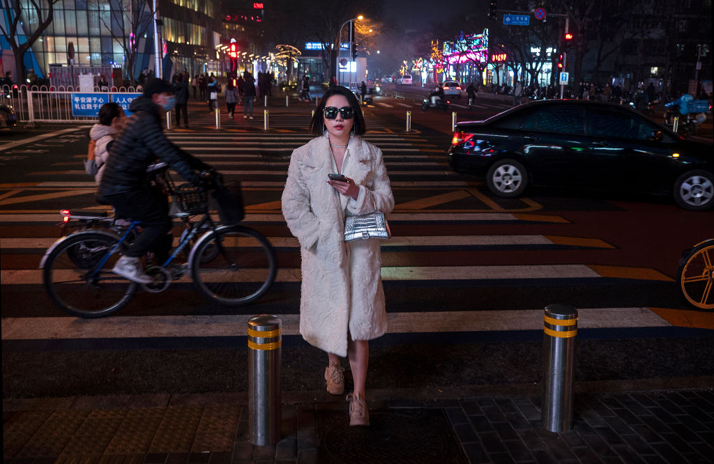A woman walks across a road in a high-end shopping district in Beijing, China, on March 24, 2022. (Kevin Frayer—Getty Images)