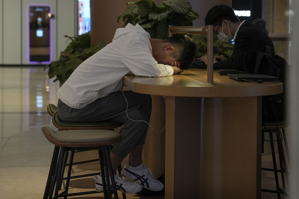 A man takes a nap at a cafe inside a mall in Beijing on May 24, 2023, as unemployment among young people in cities continues to rise. (Andy Wong—AP)