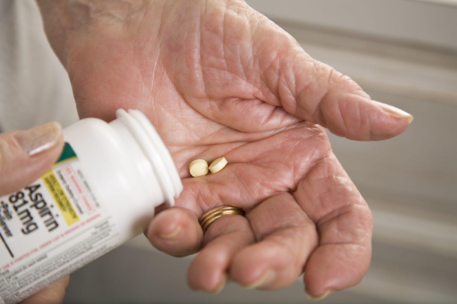 senior woman with distorted arthritis hand taking aspirin pills
