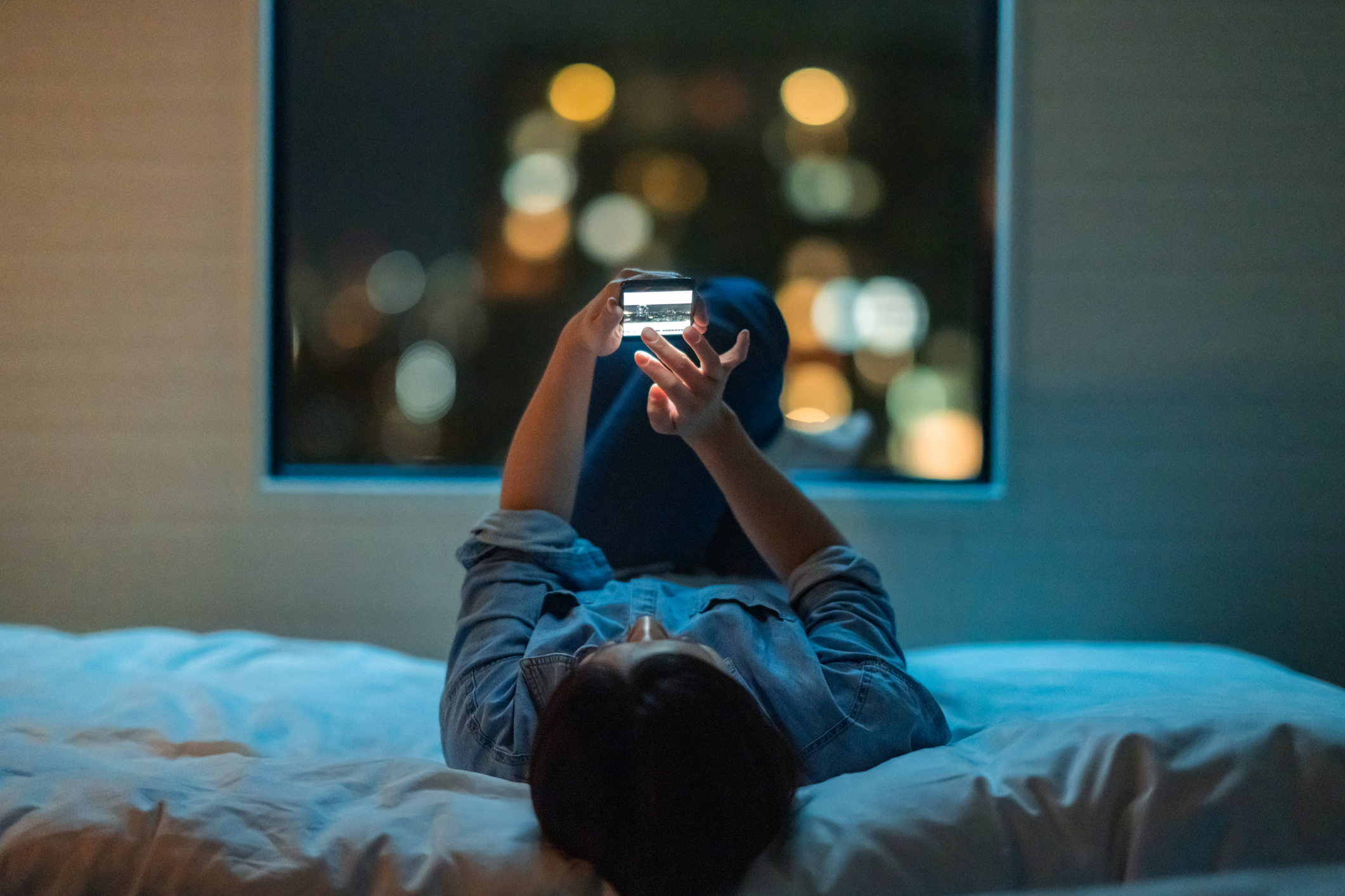 A woman (not Lim Ji-hye) lies on a bed looking at her phone. (Getty Images/iStock)