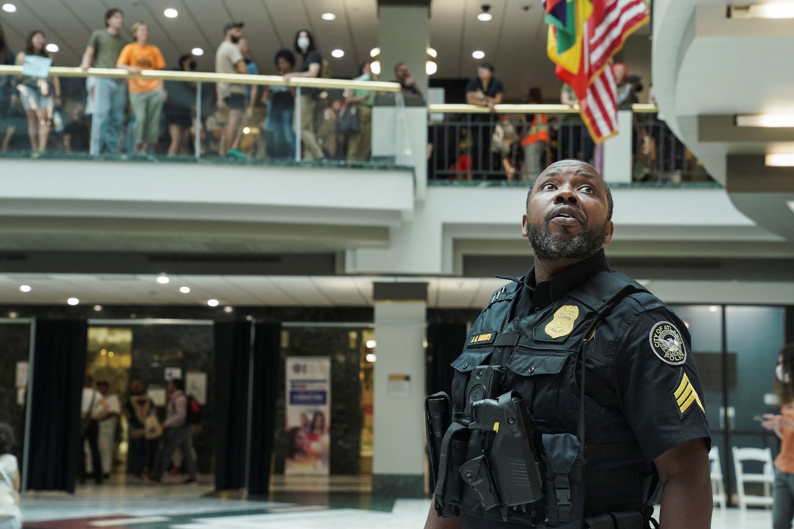 A police officer looks up as people protest against the controversial “Cop City” project, inside the city hall in Atlanta on May 15, 2023. (Megan Varner—Reuters)