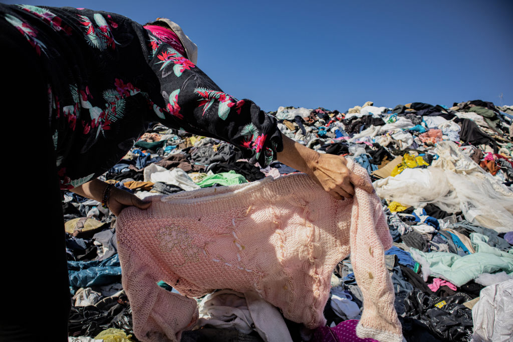 A woman searches for an item of clothing among a mountain of used clothes at a garbage dump in Chile on Nov. 25, 2021. (Antonio Cossio/dpa Picture Alliance—Getty Images)