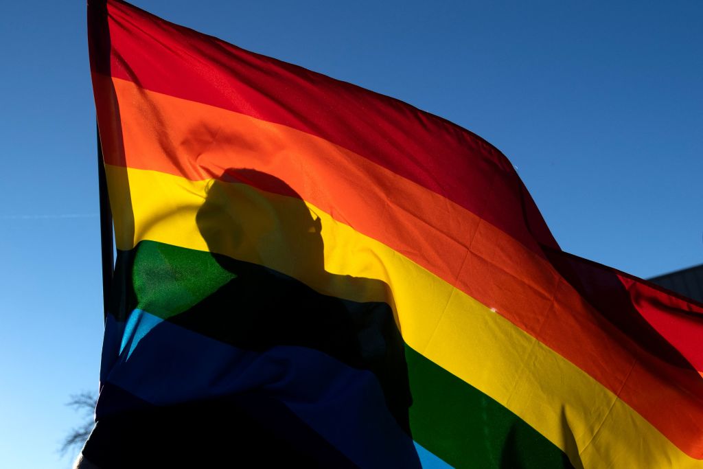 A silhouette is seen through a Pride flag while a person pays respects to the victims of the mass shooting at Club Q, in Colorado Springs, Colo., on November 20, 2022. (Jason Connolly—AFP via Getty Images)