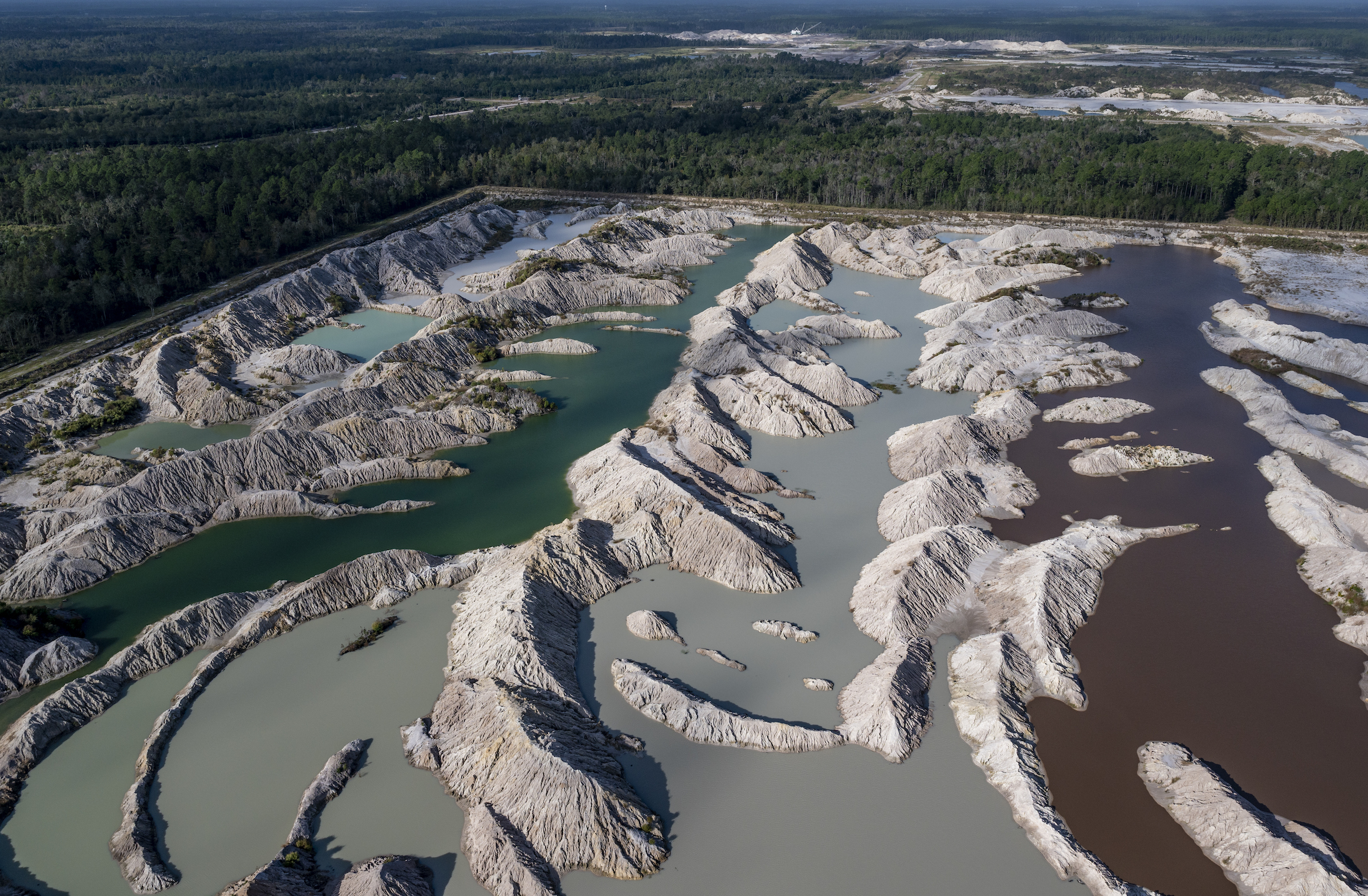 Photo by Jason Gulley. Strip mining for phosphate transforms forests into cratered moonscapes. Phosphate mines use tremendous volumes of water and supply a key ingredient for the fertilizer that is fueling algae blooms in Florida's springs and waterways. According to The Florida Industrial and Phosphate Research Institute, Florida produces about 80% of the phosphate used in the United States. Intensive phosphate mining activities just a few miles away from White Springs were initially blamed for causing White Sulfur Springs to dry up. Later research suggested soaring groundwater withdraws needed to slake the thirst of the expanding city of Jacksonville, nearly 50 miles to the east, may have shifted a groundwater divide. Photo over Nutrien's Swift Creek Phosphate Mine Complex, near White Springs.