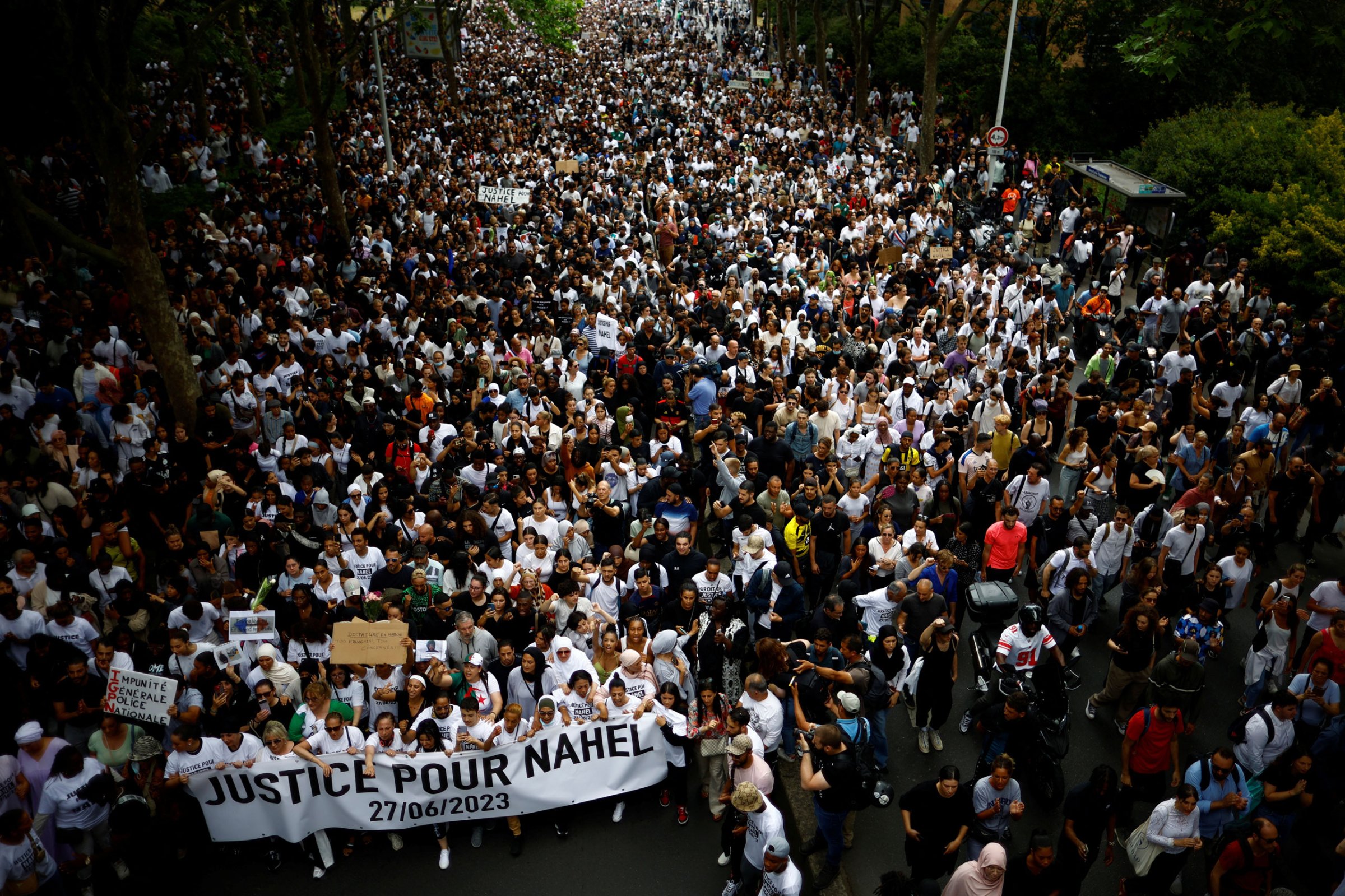 People attend a march in tribute to Nahel, a 17-year-old teenager killed by a French police officer during a traffic stop, in Nanterre, Paris, on June 29, 2023. The sign’s slogan reads “Justice for Nahel.”