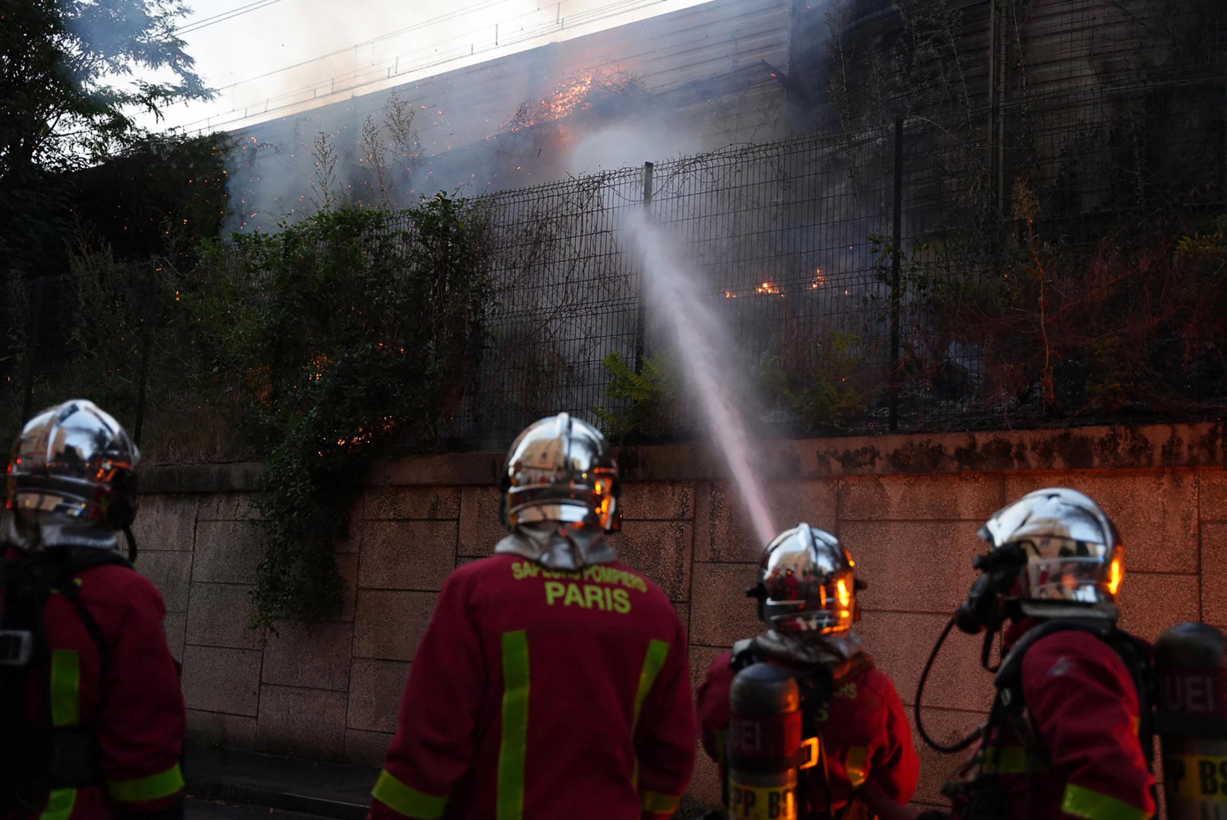 Firefighters work to put out a fire on the sidelines of a demonstration in Nanterre