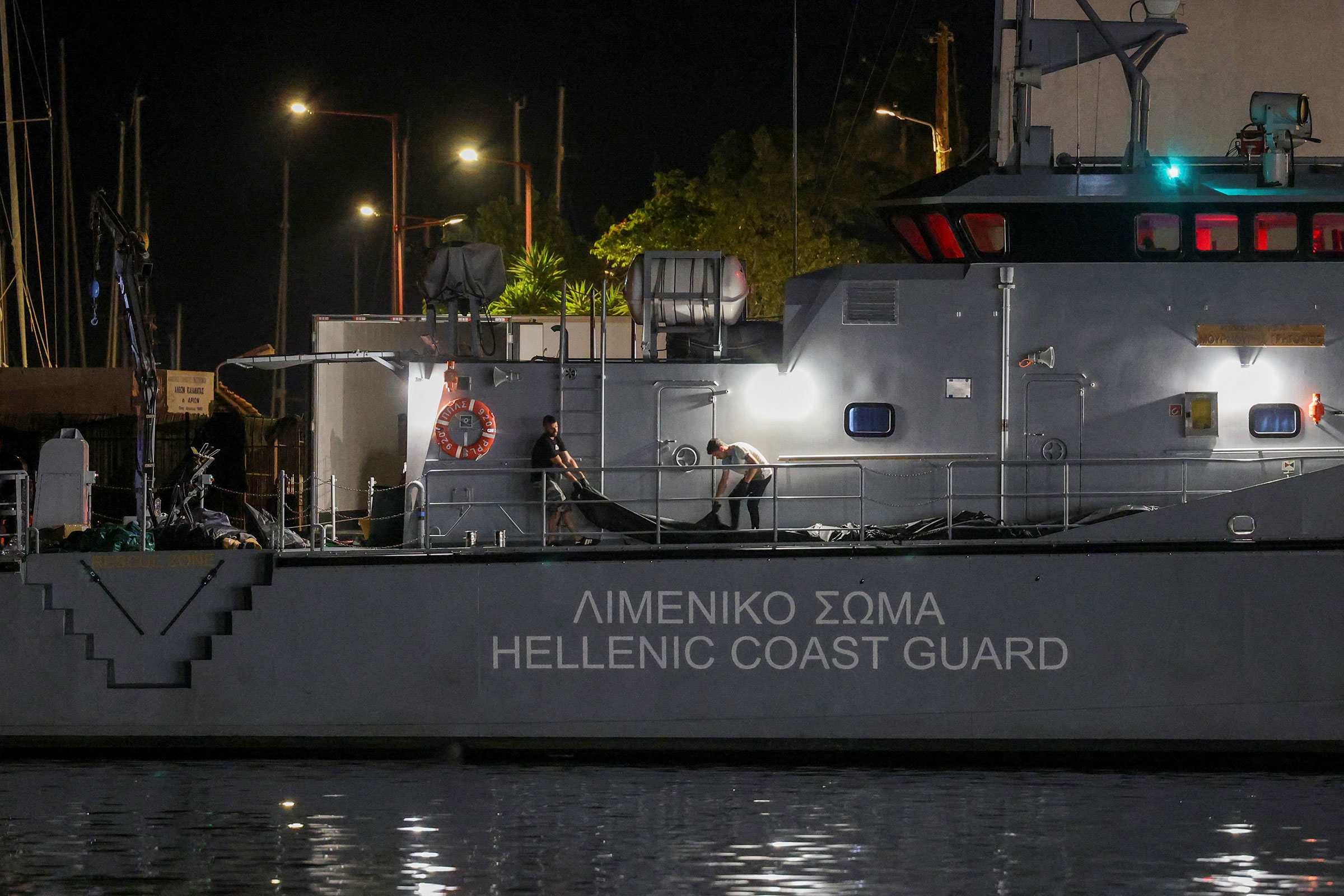 People transfer body bags carrying migrants who died after their boat capsized in the open sea off Greece, onboard a Hellenic Coast Guard vessel at the port of Kalamata, Greece, on June 14, 2023. (Stelios Misinas—Reuters)