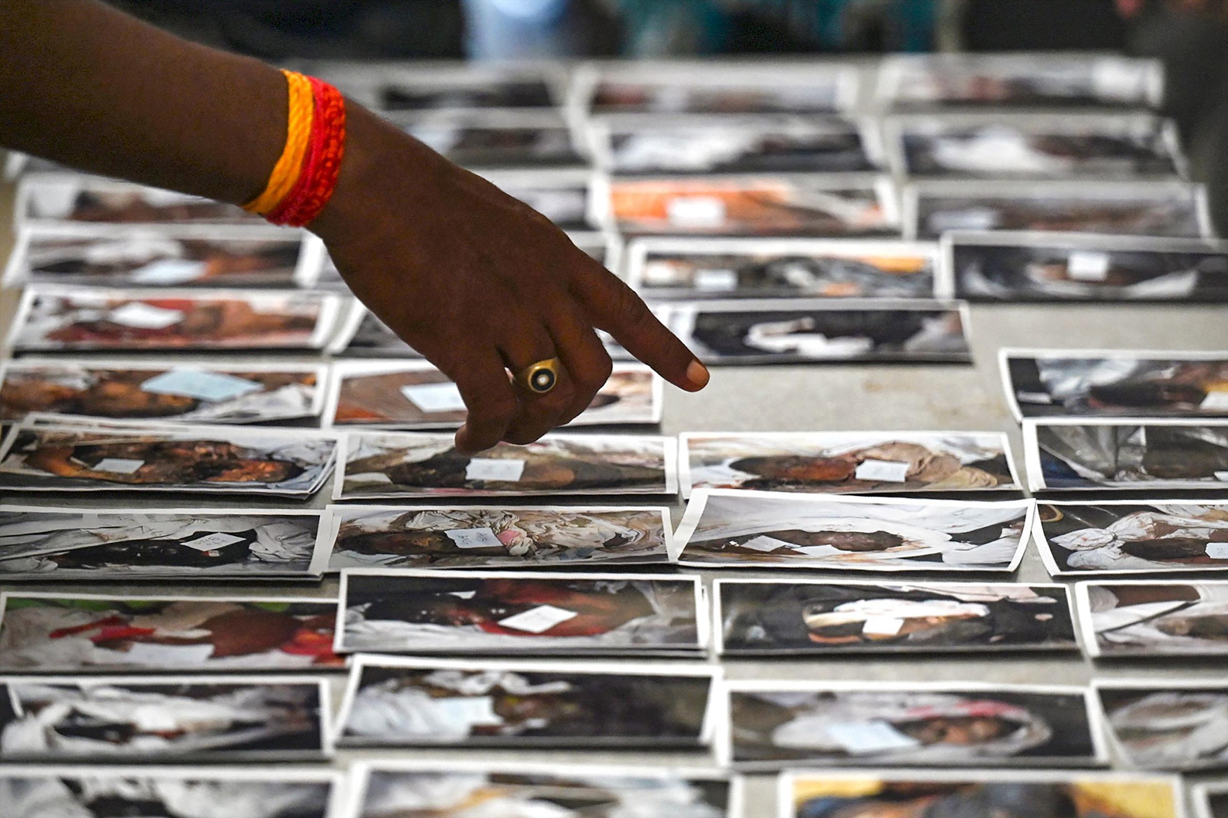 A victim's family member looks at photographs to identify the body, at a business park used as temporary mortuary for the dead recovered from the three-train collision, near Balasore on June 4. (Punit Paranjpe—AFP/Getty Images)