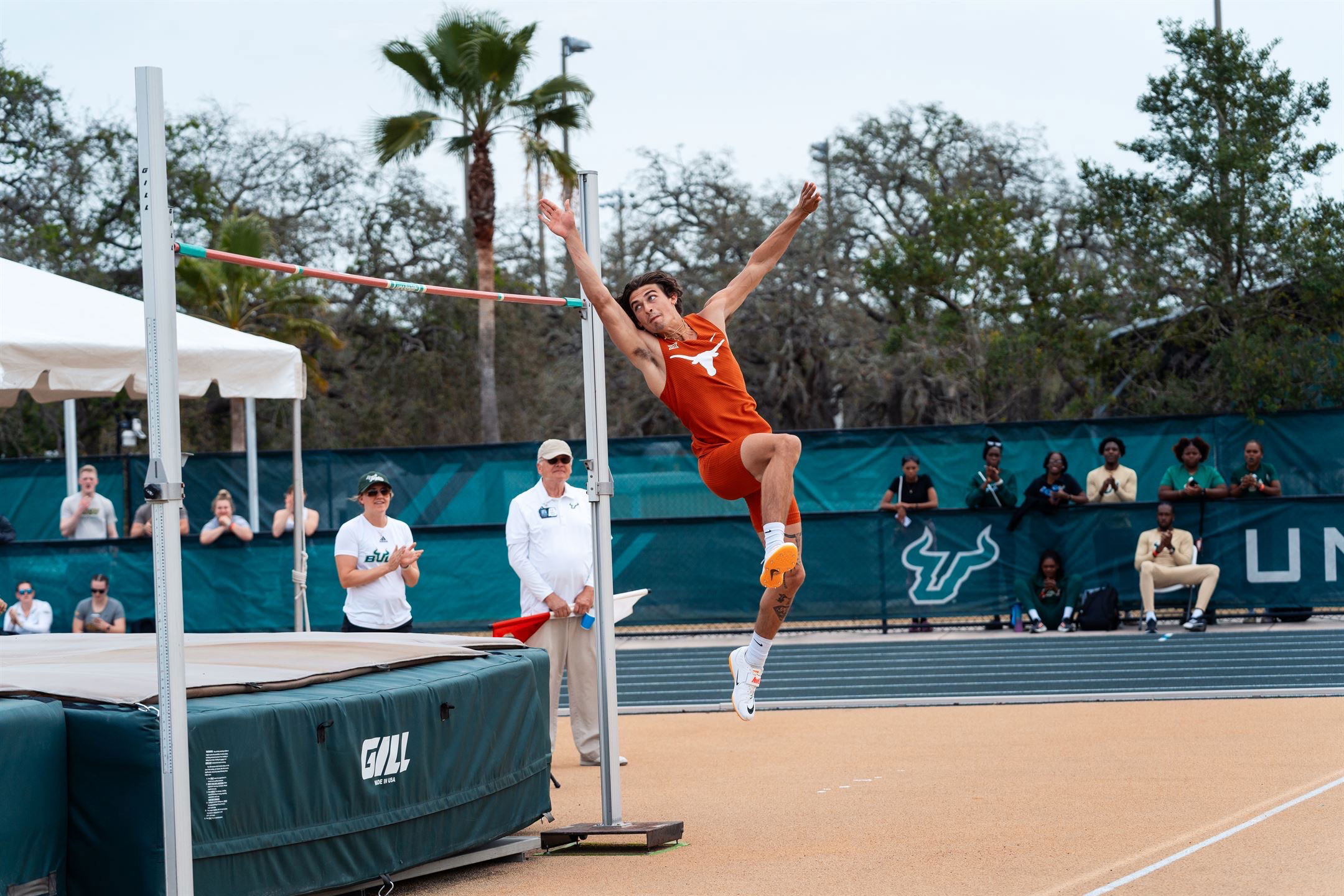Sam Hurley leaping in a high jump competition, wearing a University of Texas uniform