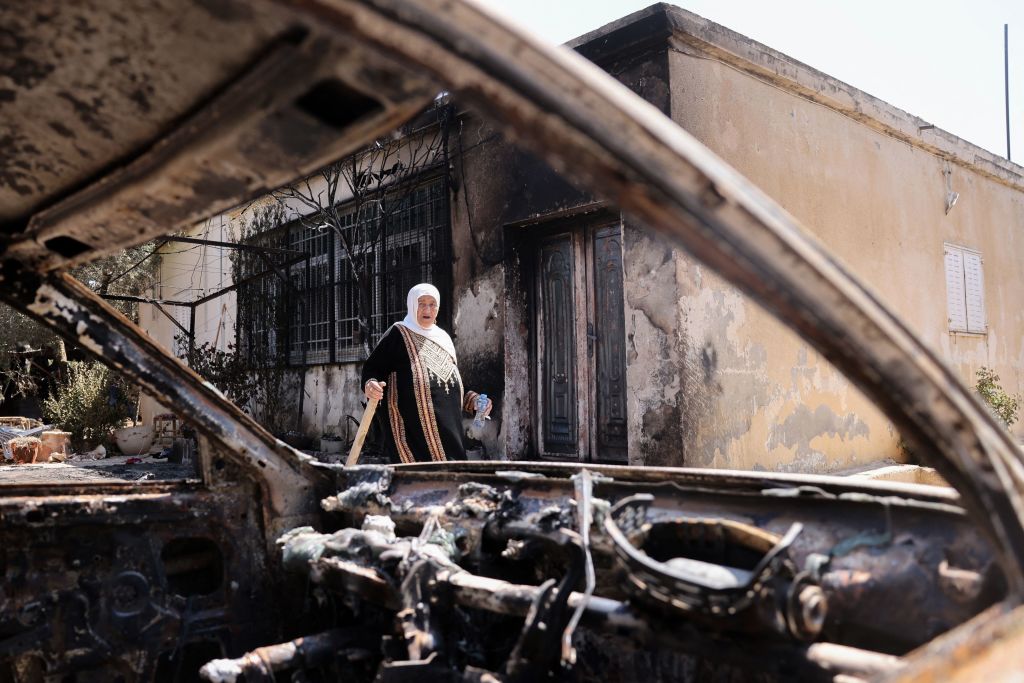 A Palestinian woman carries a piece of wood as she stands outside her house, which was set on fire by Israeli settlers the day before, in Turmus Ayya near the occupied West Bank city of Ramallah, on June 22, 2023. (AFP—Getty Images)