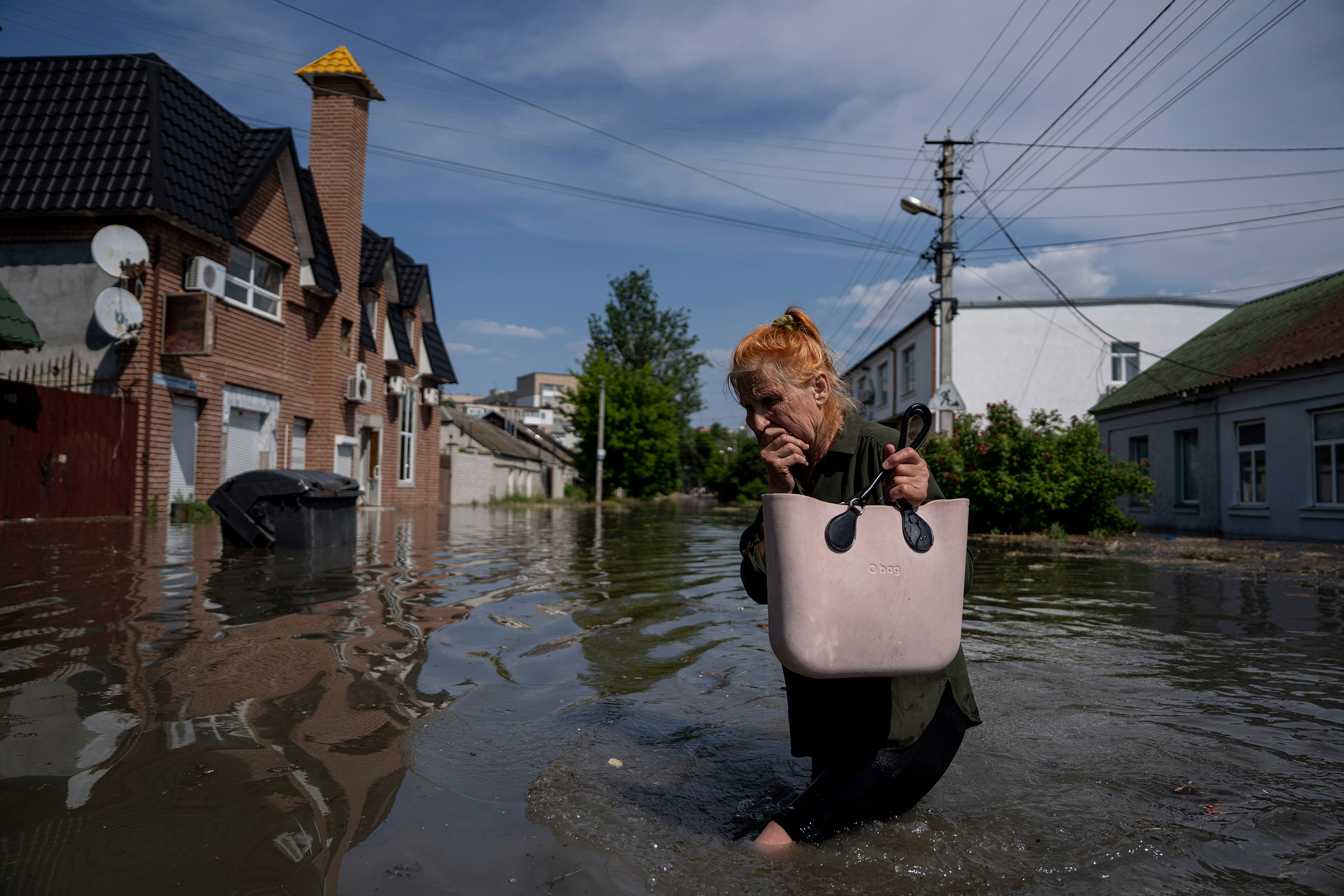 A local resident makes her way through a flooded road after the walls of the Kakhovka dam collapsed overnight, in Kherson, Ukraine, on Jun 6.