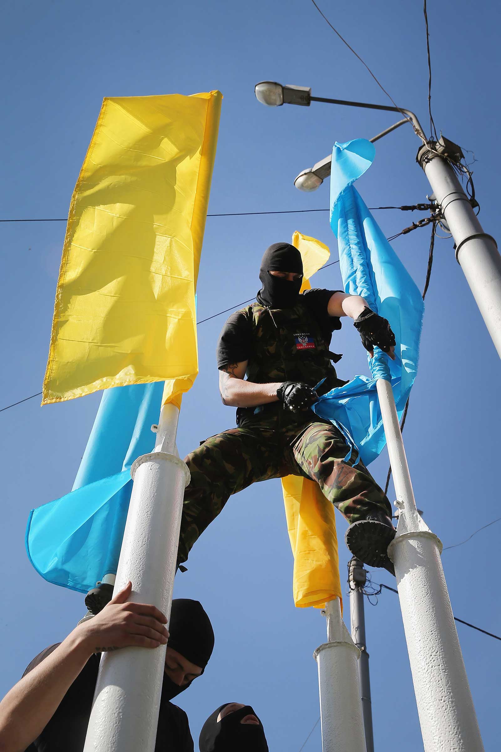 A pro-Russian separatist tears down Ukrainian banners near a TV station in Donetsk in April 2014. (Scott Olson—Getty Images)