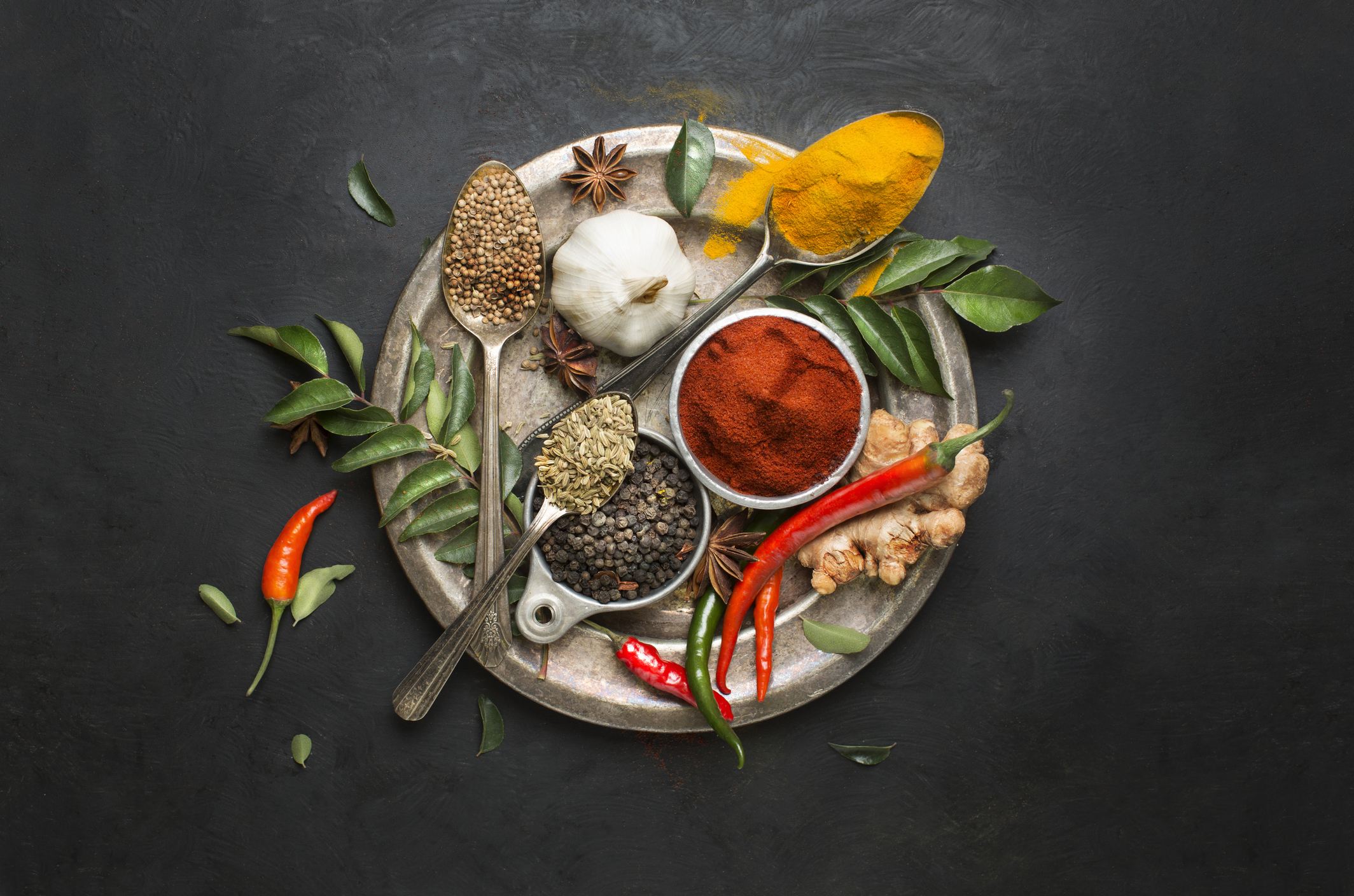 Flat lay overhead view herb and spices on textured black background.
