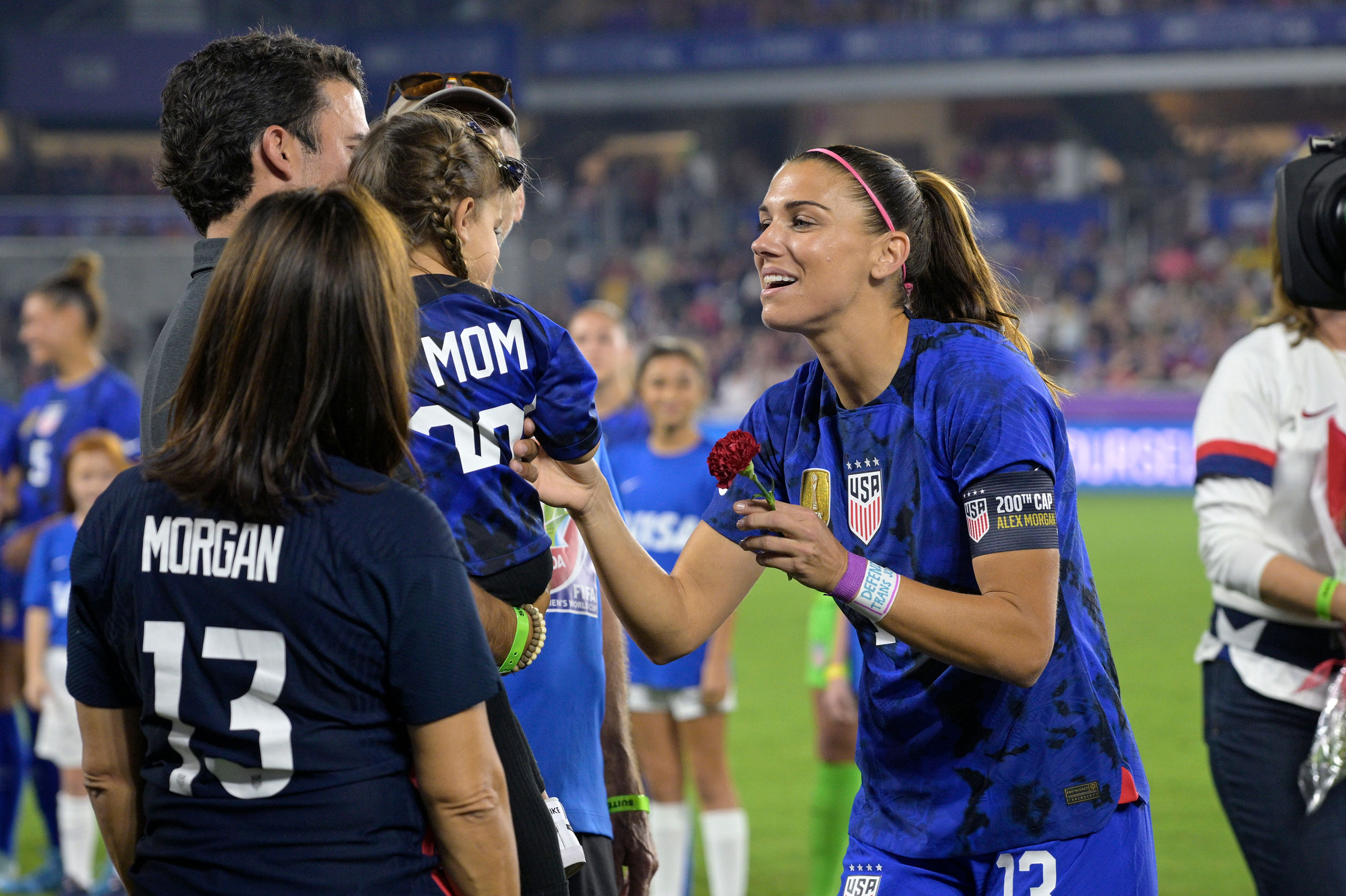 Alex Morgan receives a flower from her daughter Charlie, with husband Servando Carrasco, while being honored for her 200th appearance for the U.S. women’s national team before a SheBelieves Cup match against Canada, in Orlando, Fla., on Feb. 16, 2023. (Phelan M. Ebenhack—AP)