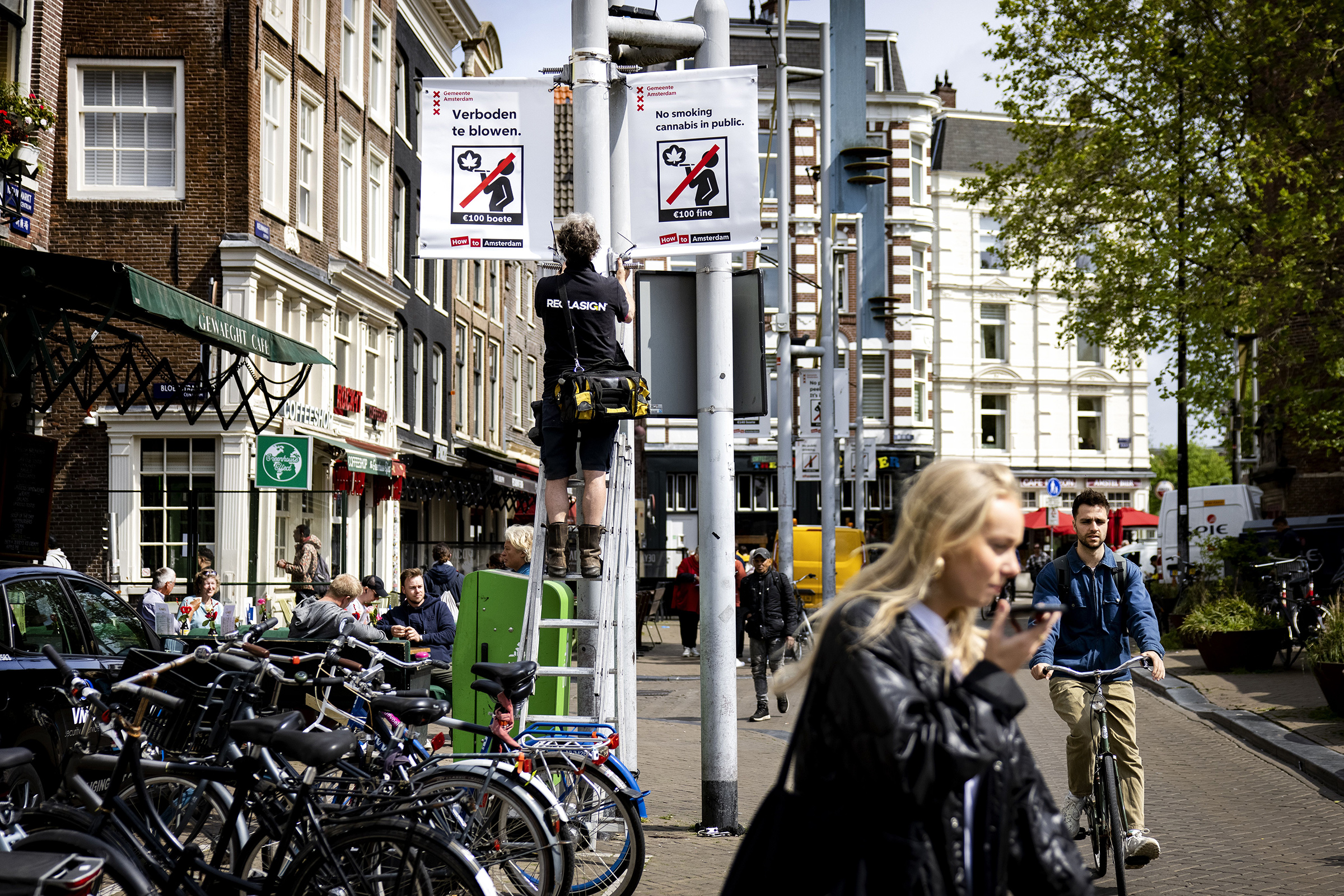 An employee of the municipality places a prohibition sign on the Nieuwmarkt on May 23. From May 25, it is forbidden to smoke weed in the old city center of Amsterdam. (Hollandse Hoogte—Shutterstock)