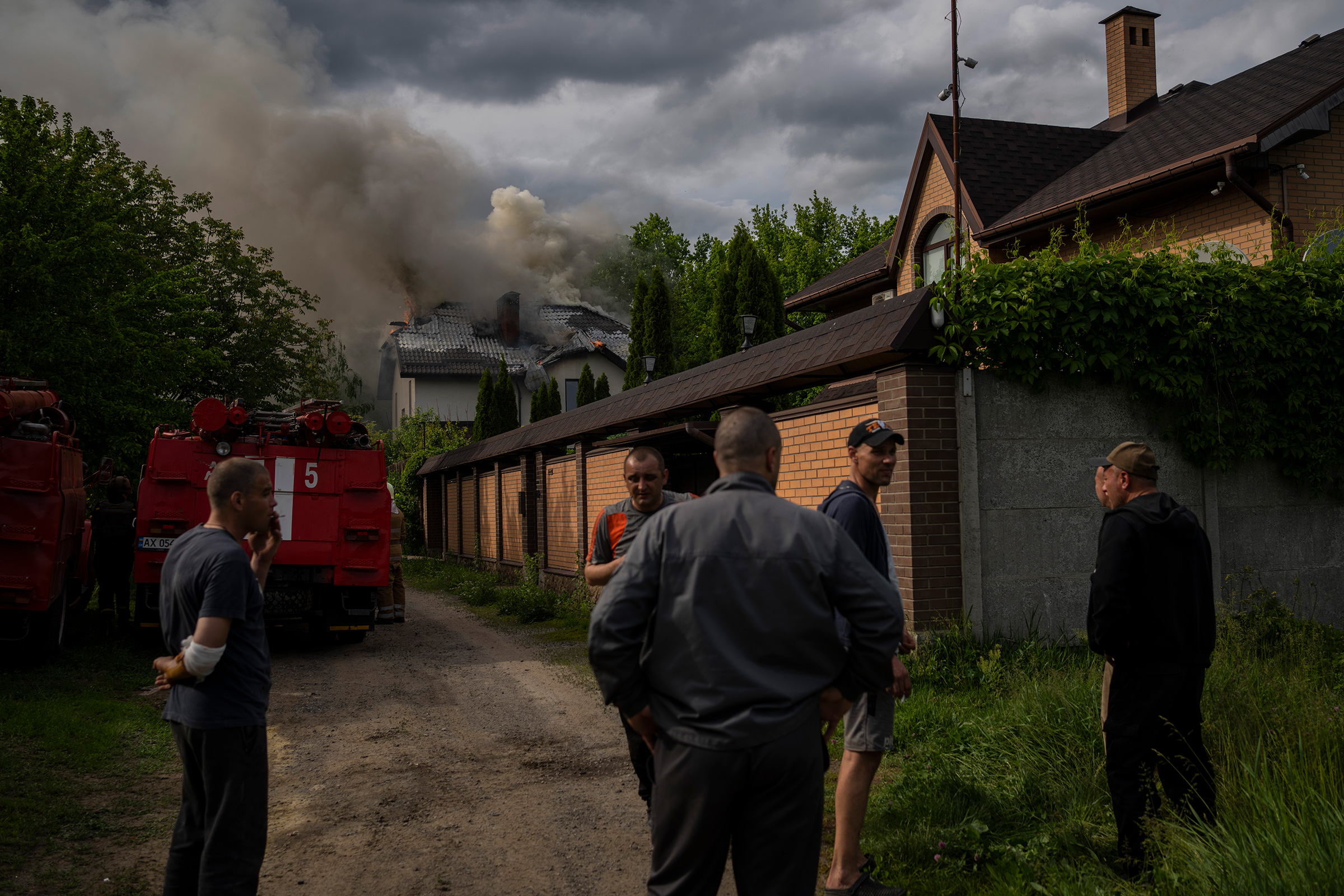 Neighbors gather around a house on fire that was hit during a Russian attack