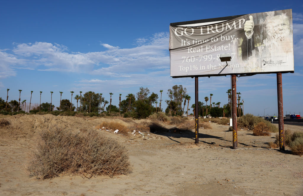 A faded billboard reads 'Go Trump It's time to buy Real Estate!' on July 13, 2022