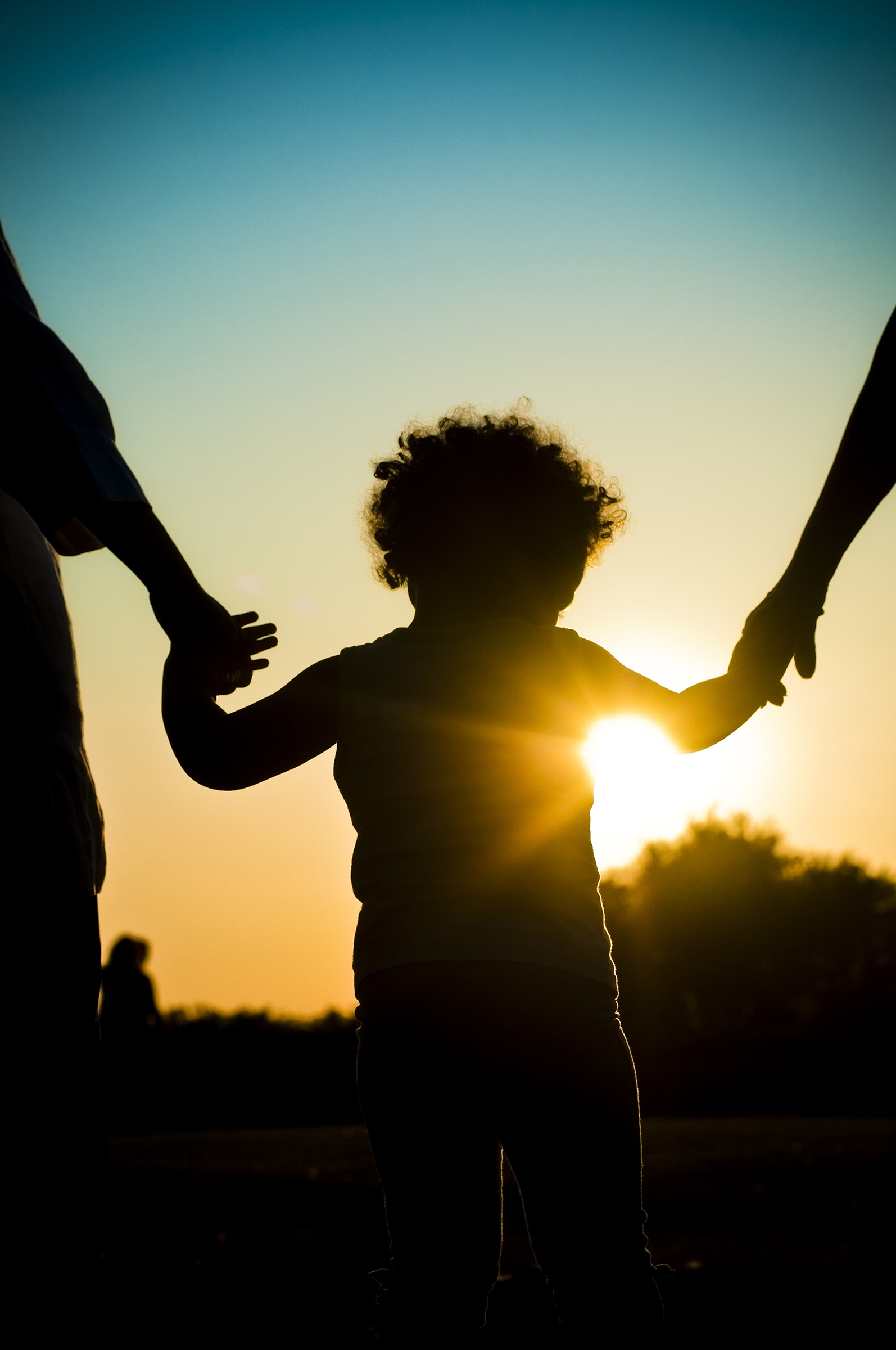 Silhouette of child holding hands with parents