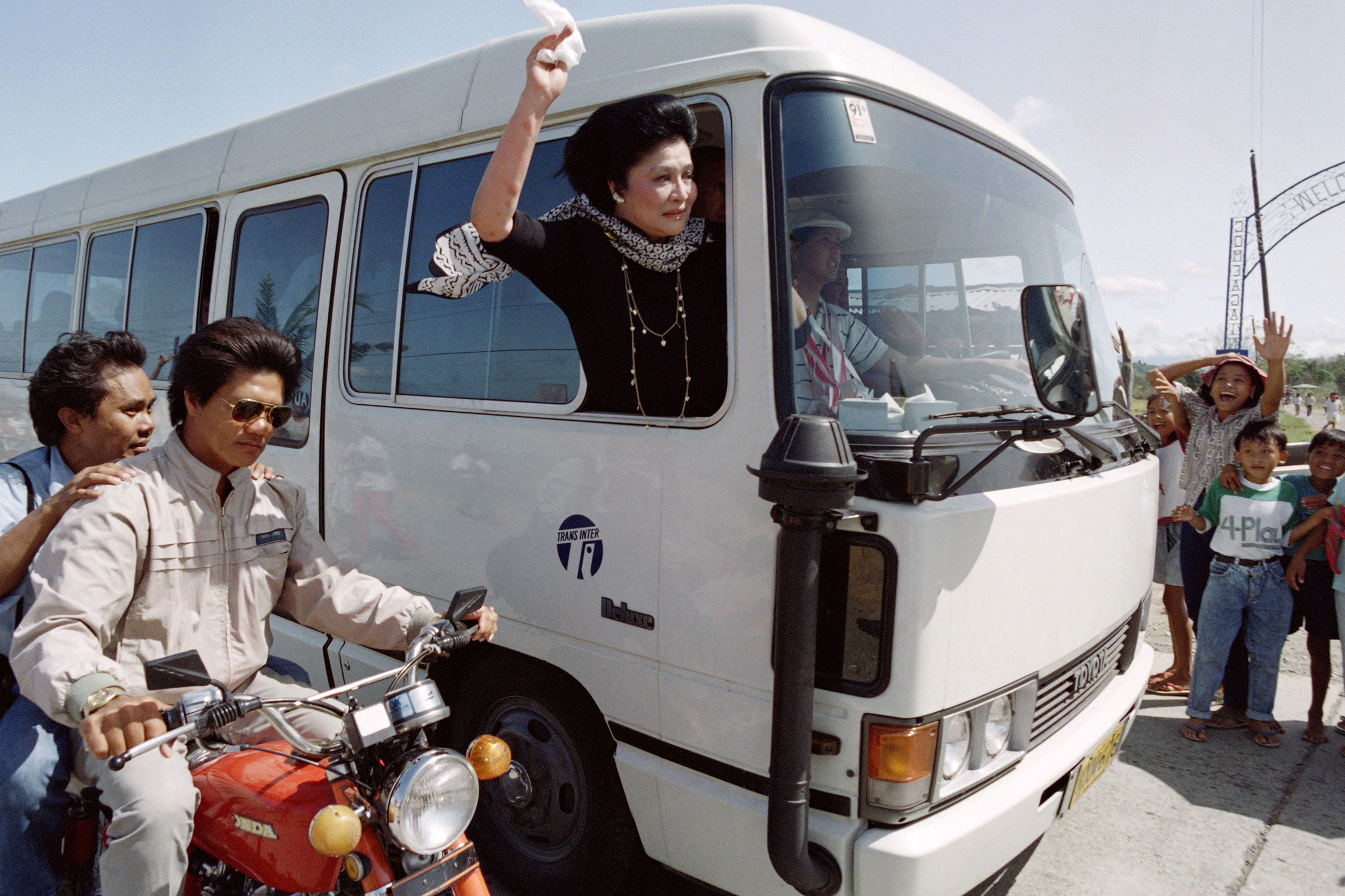 Imelda Marcos waves from a motorcade as she arrives in Laoag, the hometown of her late husband Ferdinand, on November 5, 1991. (Manny Ceneta—AFP/Getty Images)