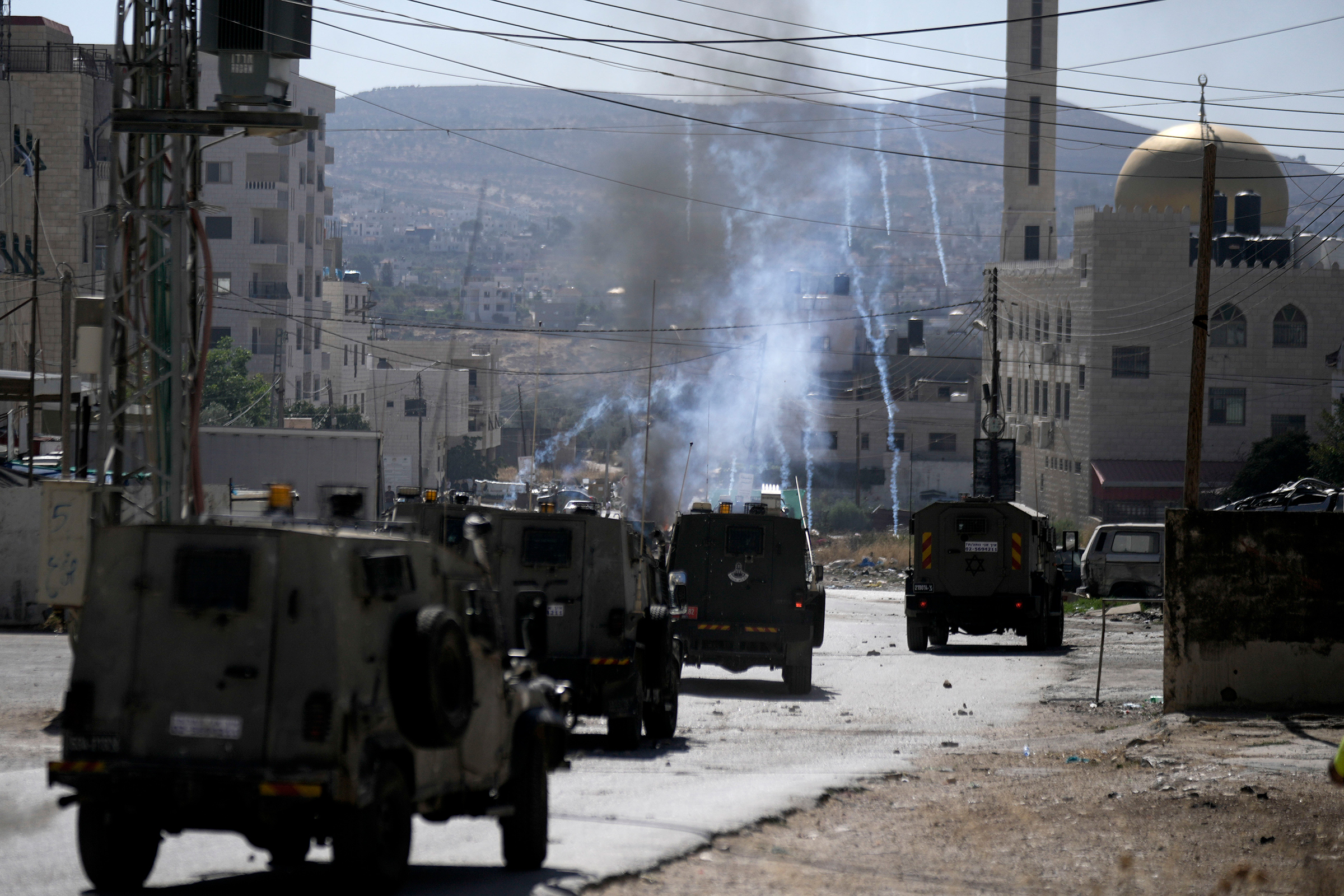 An Israeli military vehicle fires tear gas towards Palestinian protesters during a military raid in the Askar refugee camp the West Bank city of Nablus on July 24.