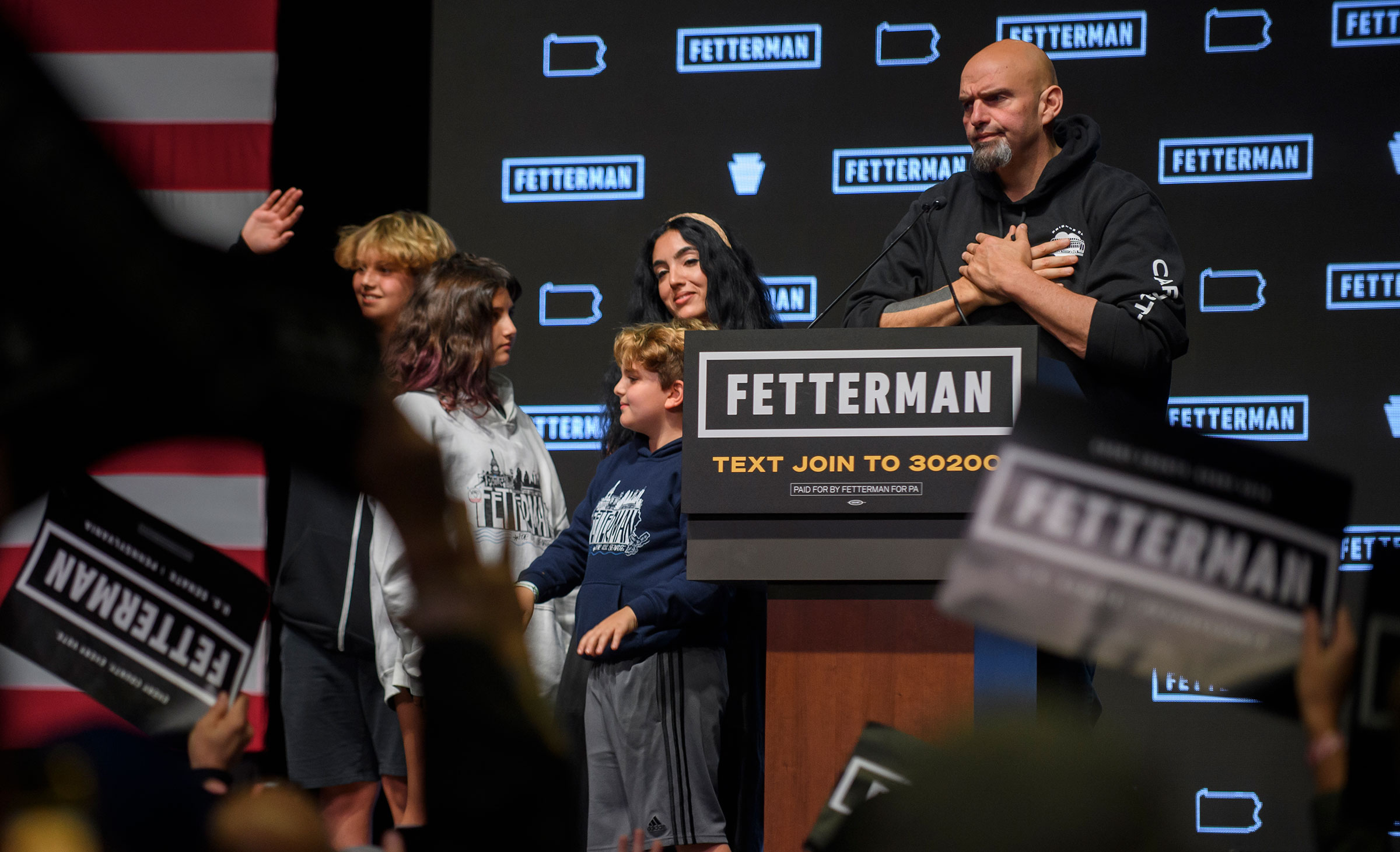 John Fetterman holds his hands to his chest in gratitude as he and his family look out at a crowd of supporters during an election night event