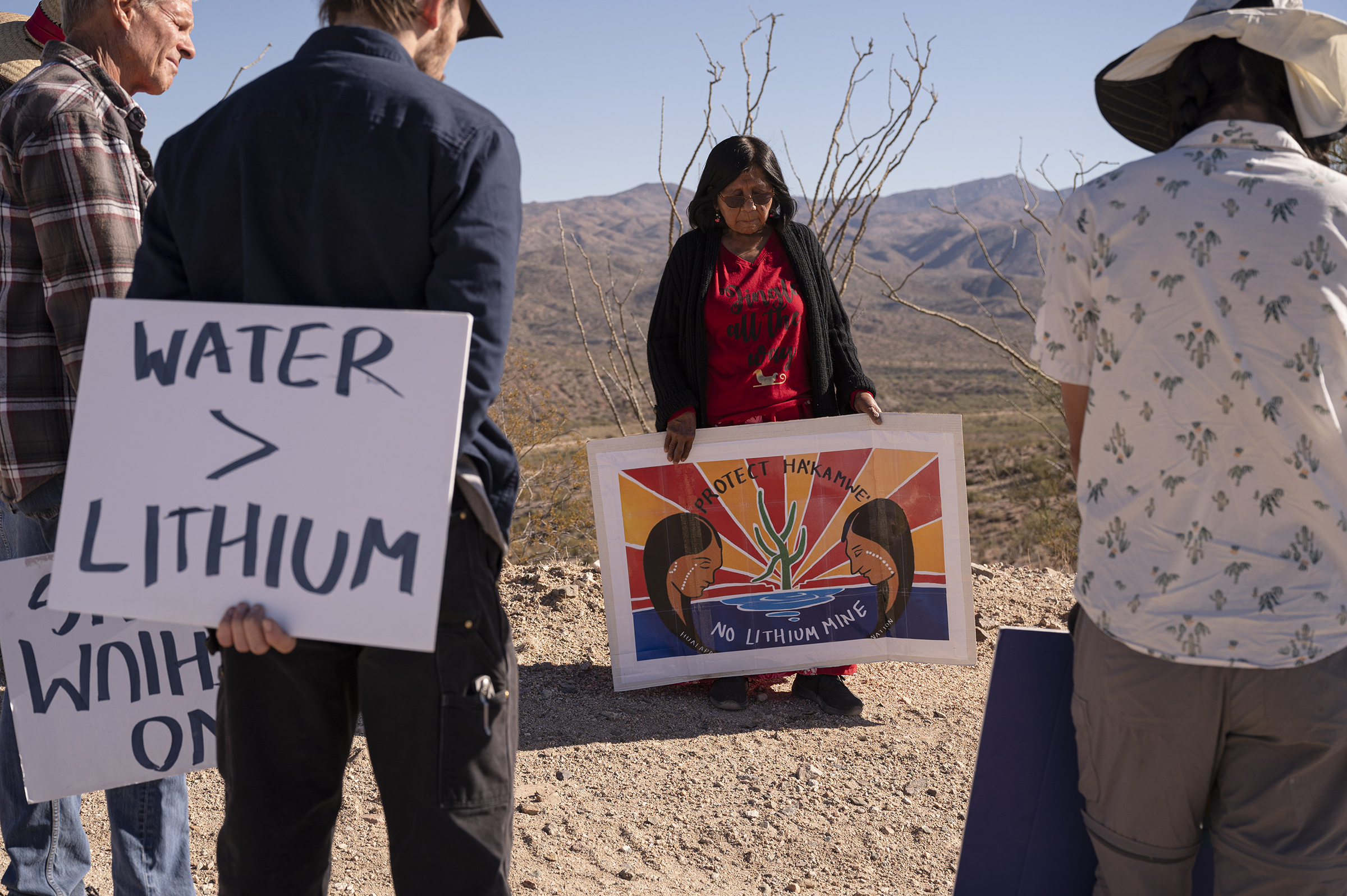 Former Hualapai tribal leader Carrie Imus holds a sign as demonstrators walk though the desert during a rally against the Hawkstone Mining Big Sandy Lithium Project in Wikieup, Ariz., on Dec. 4, 2021. Demonstrators believe that the mine poses a threat to the water supply during an ongoing severe drought. (Bridget Bennett—Bloomberg/Getty Images)
