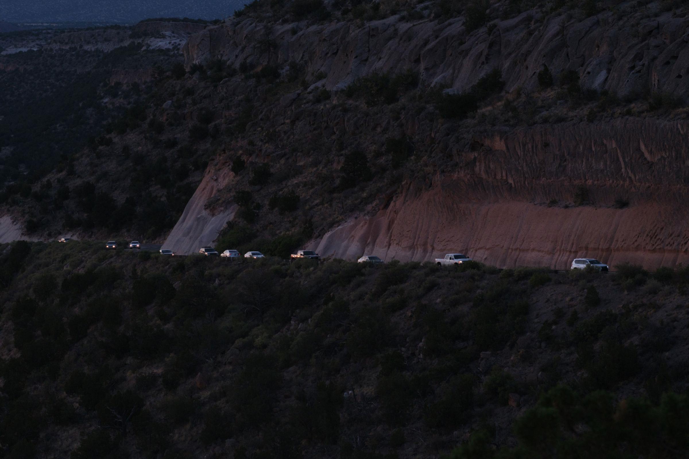 cars lined up on a road leading into Los Alamos
