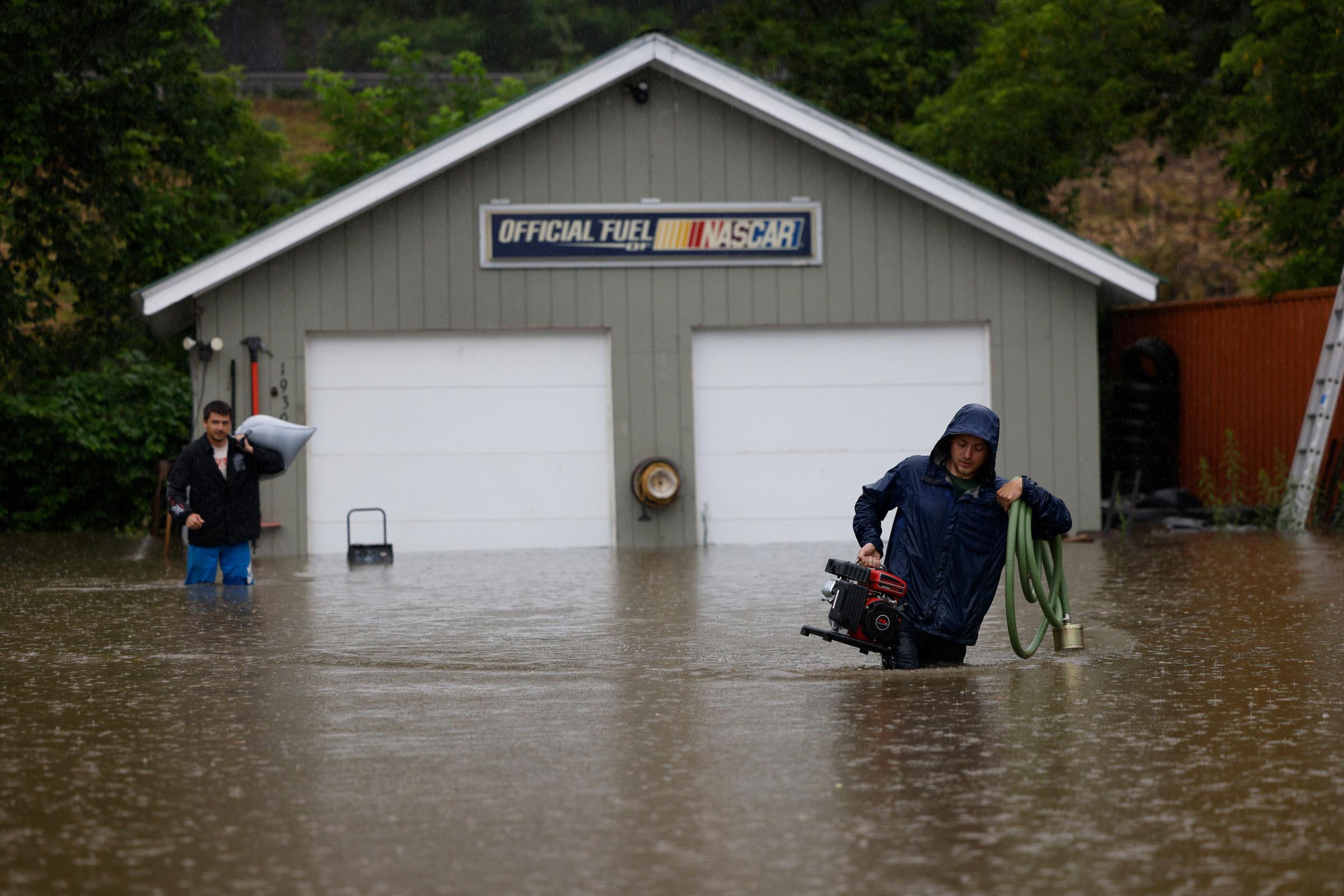 Residents remove their possessions from their home as floodwaters rise