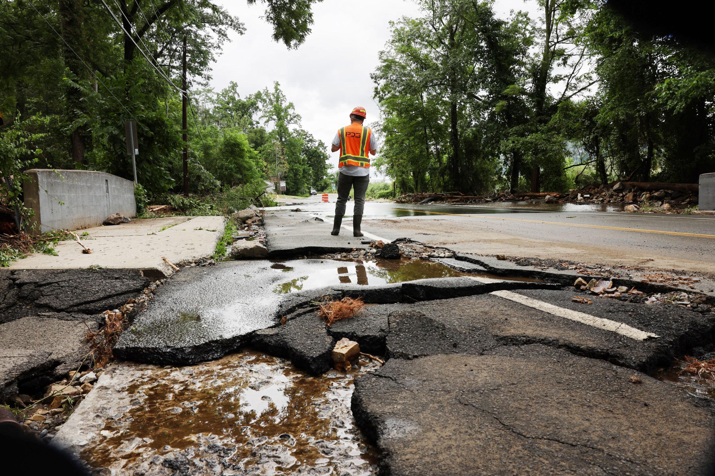 Workers survey a severely damaged road near Bear Mountain State Park following a night of heavy rain