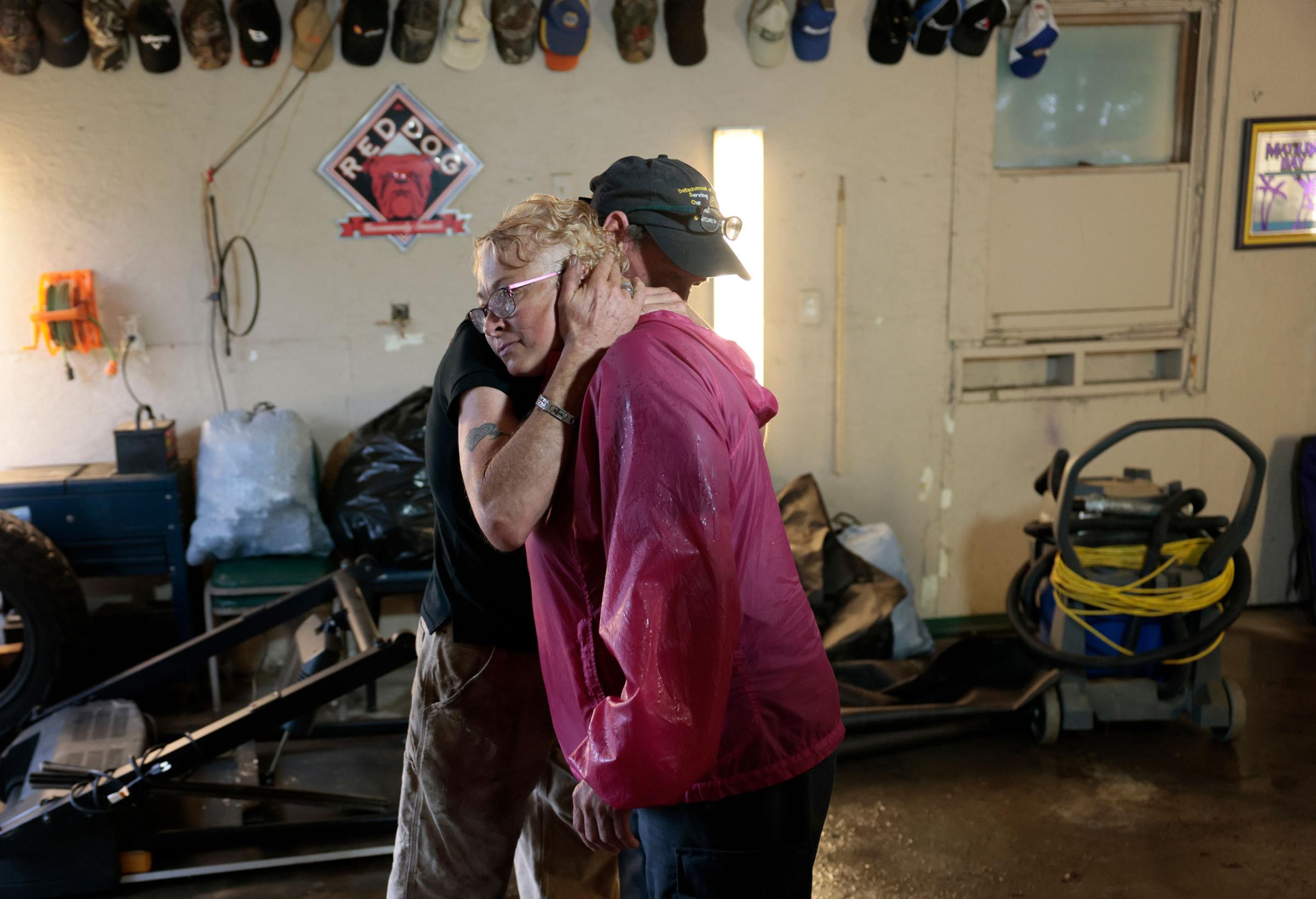 Clement Despault, left, embraces his friend Kim Crowell inside her garage as the water rises on both sides around her home