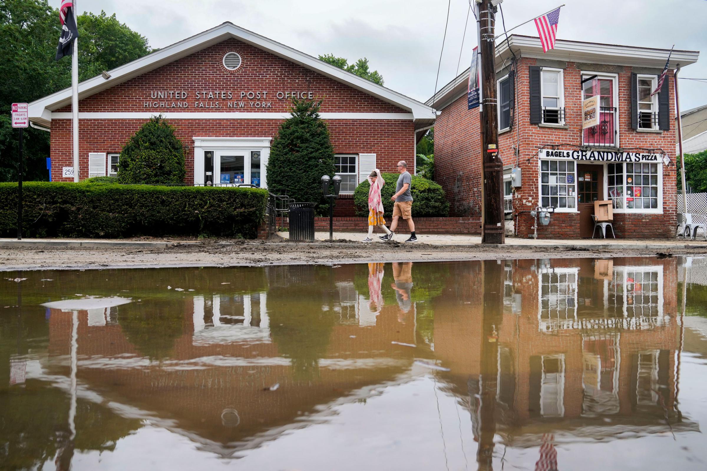 Pedestrians pass along Main Street that was damaged by flooding